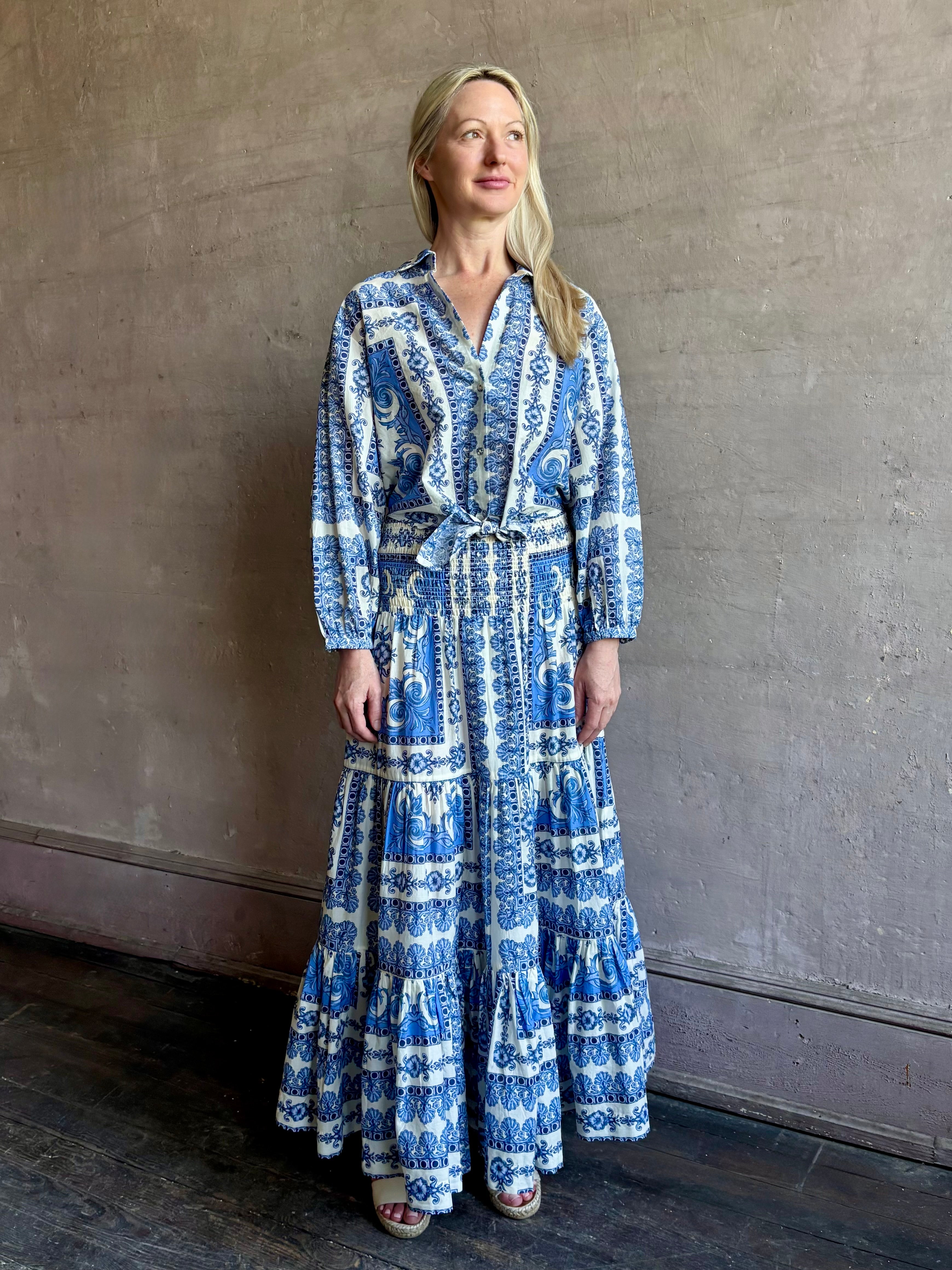 Mature woman wearing Emilia Skirt from Cara Cara rendered in the Hudson Scarf Sky blue and white print crafted from 100% cotton with shirred drop waist and ruffled tiered full skirt