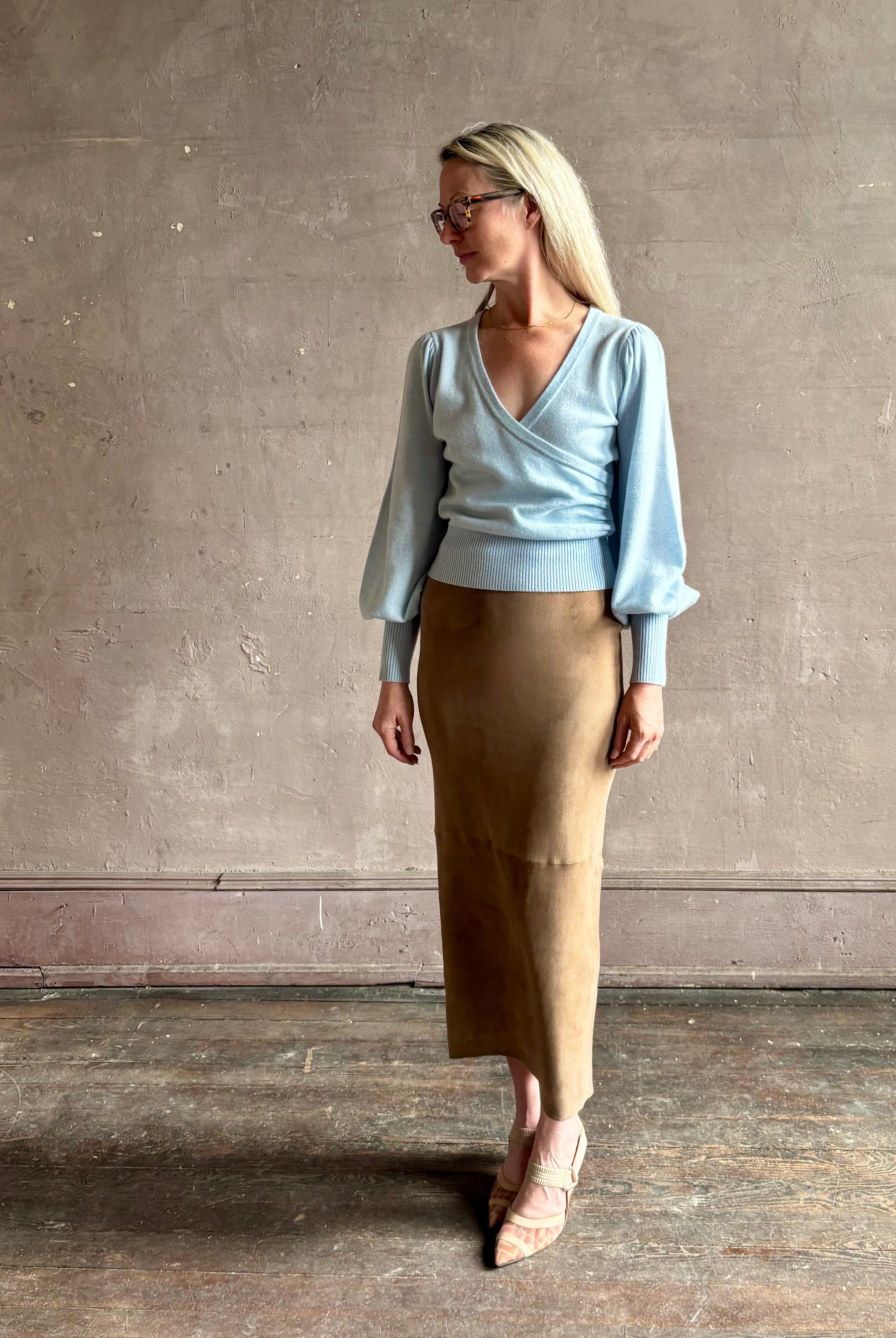 mature woman wearing designer Cara Cara wool-cashmere blend light blue wrap sweater v-neck and long sleeves
