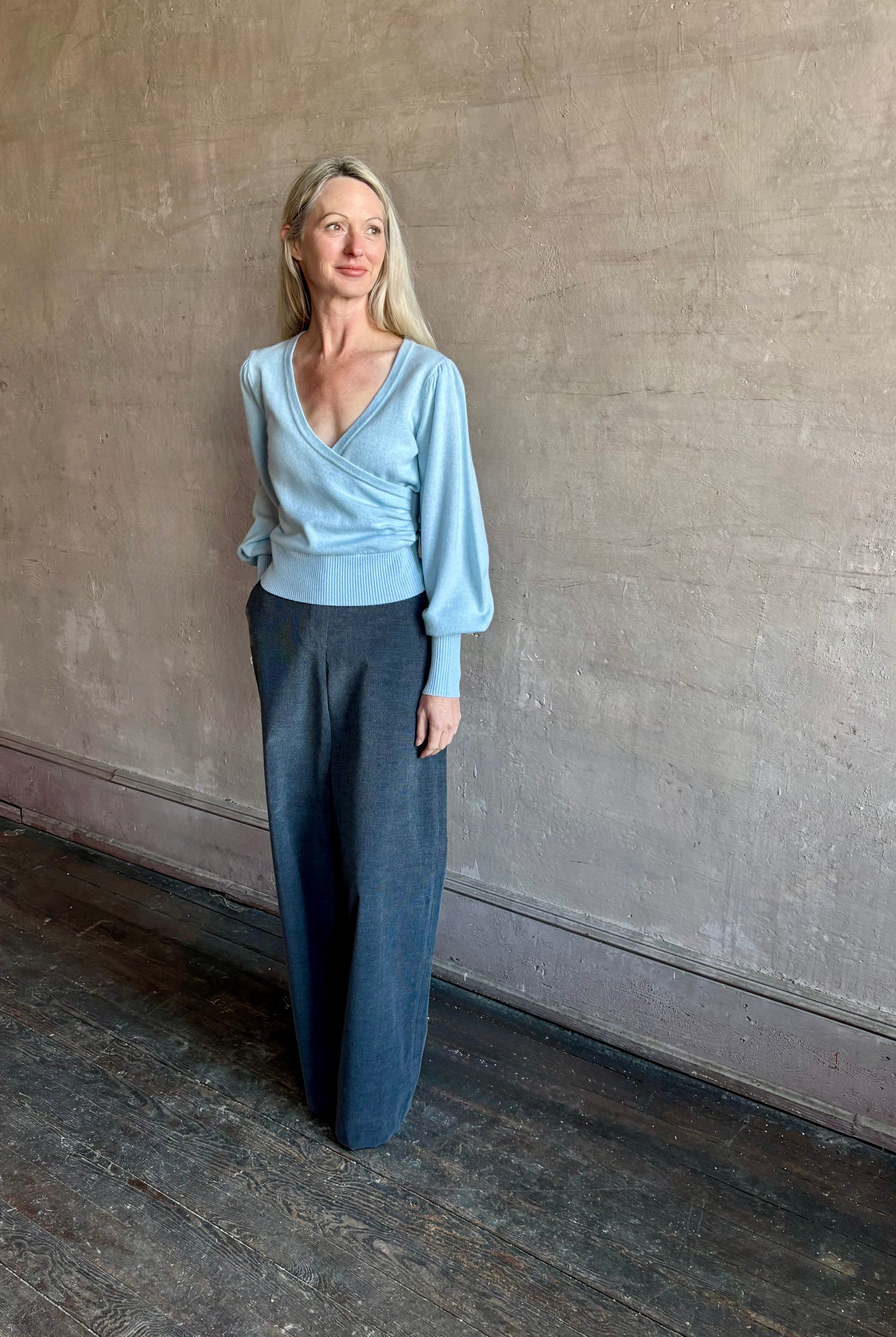 Image of mature woman wearing designer Cara Cara wool-cashmere blend light blue wrap sweater with a v-neck and long sleeves
