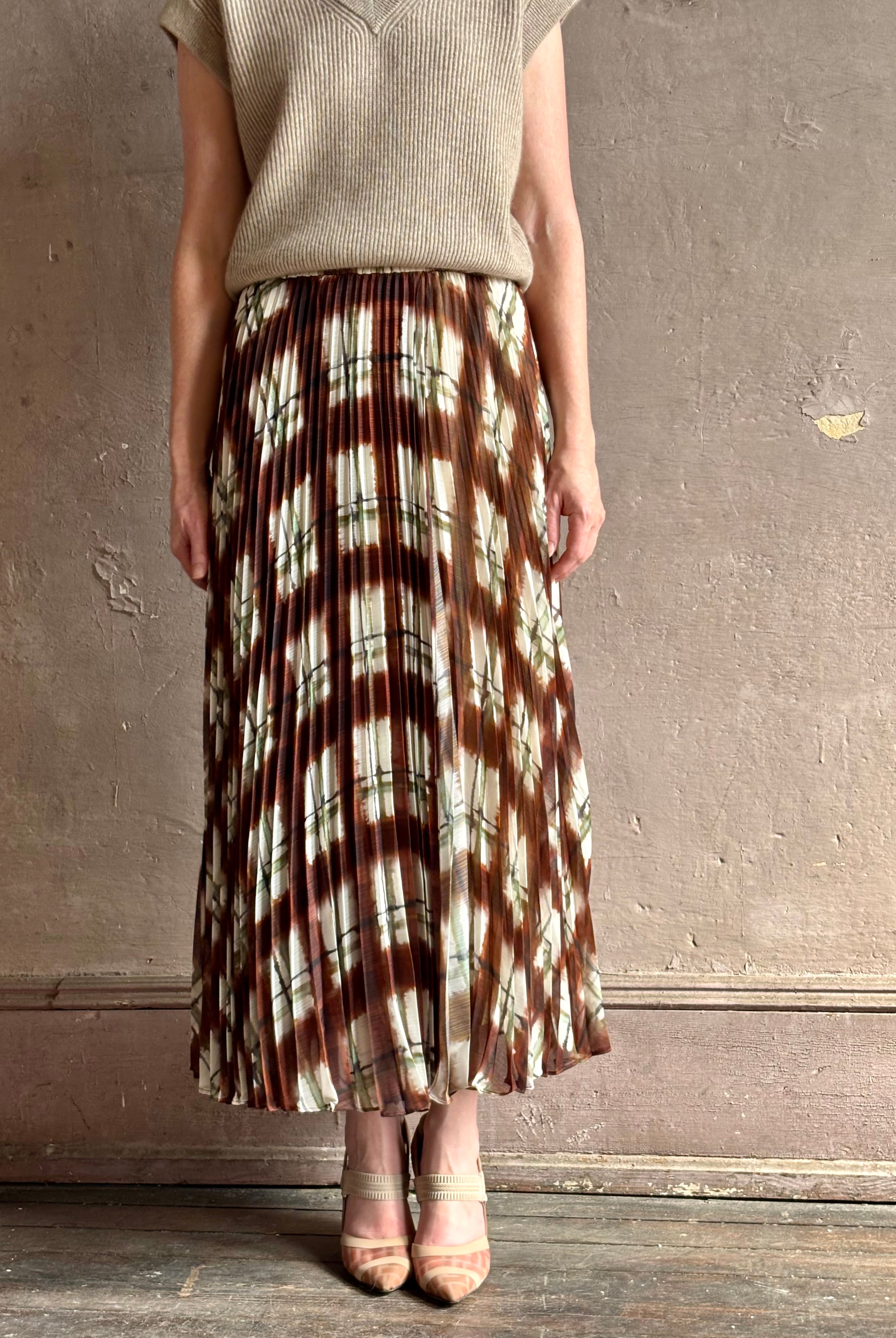 Mature woman wearing designer Cara Cara brown, cream, and green plaid patterned pleated otta maxi skirt