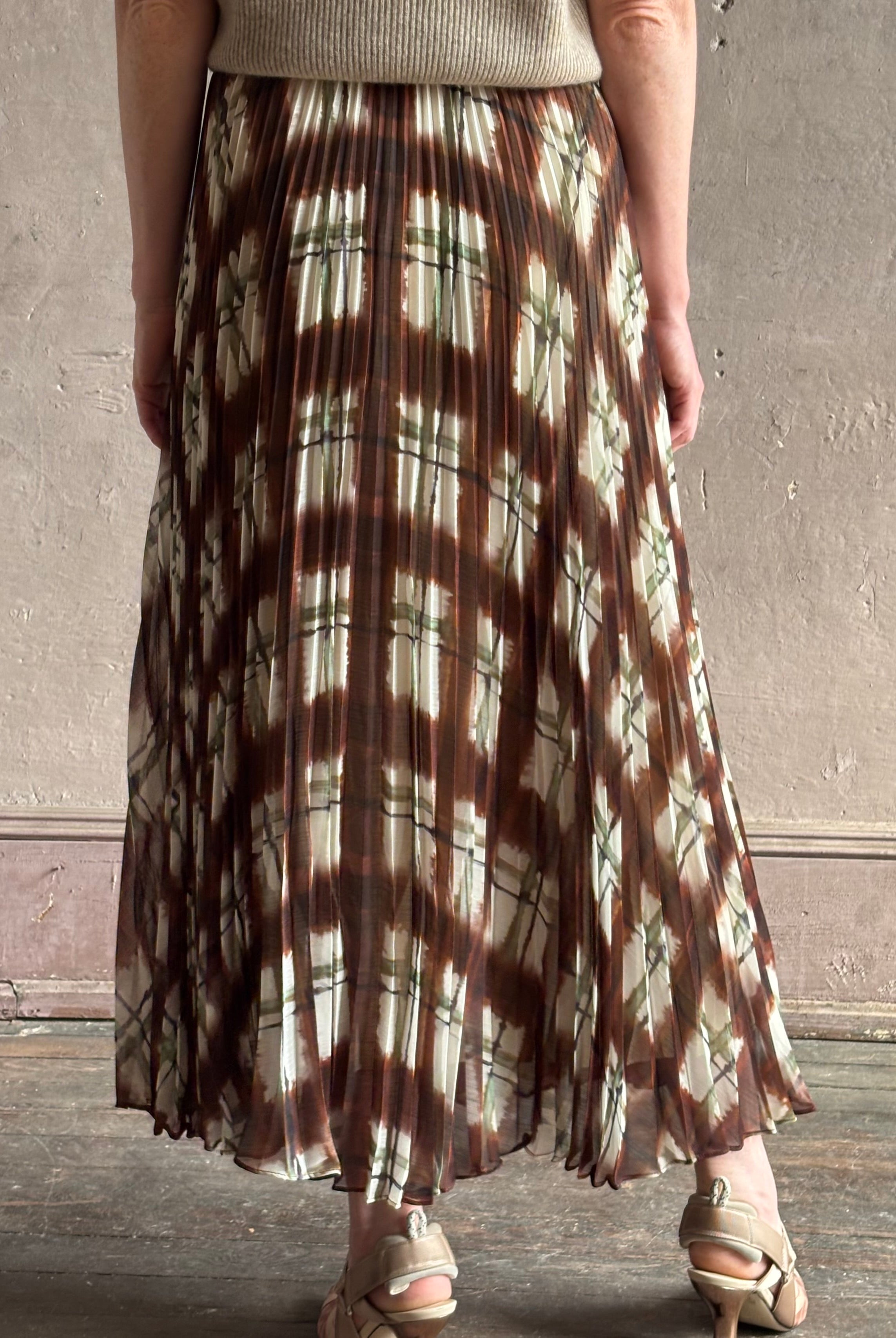 Mature woman wearing designer Cara Cara brown, cream, and green plaid patterned pleated otta maxi skirt
