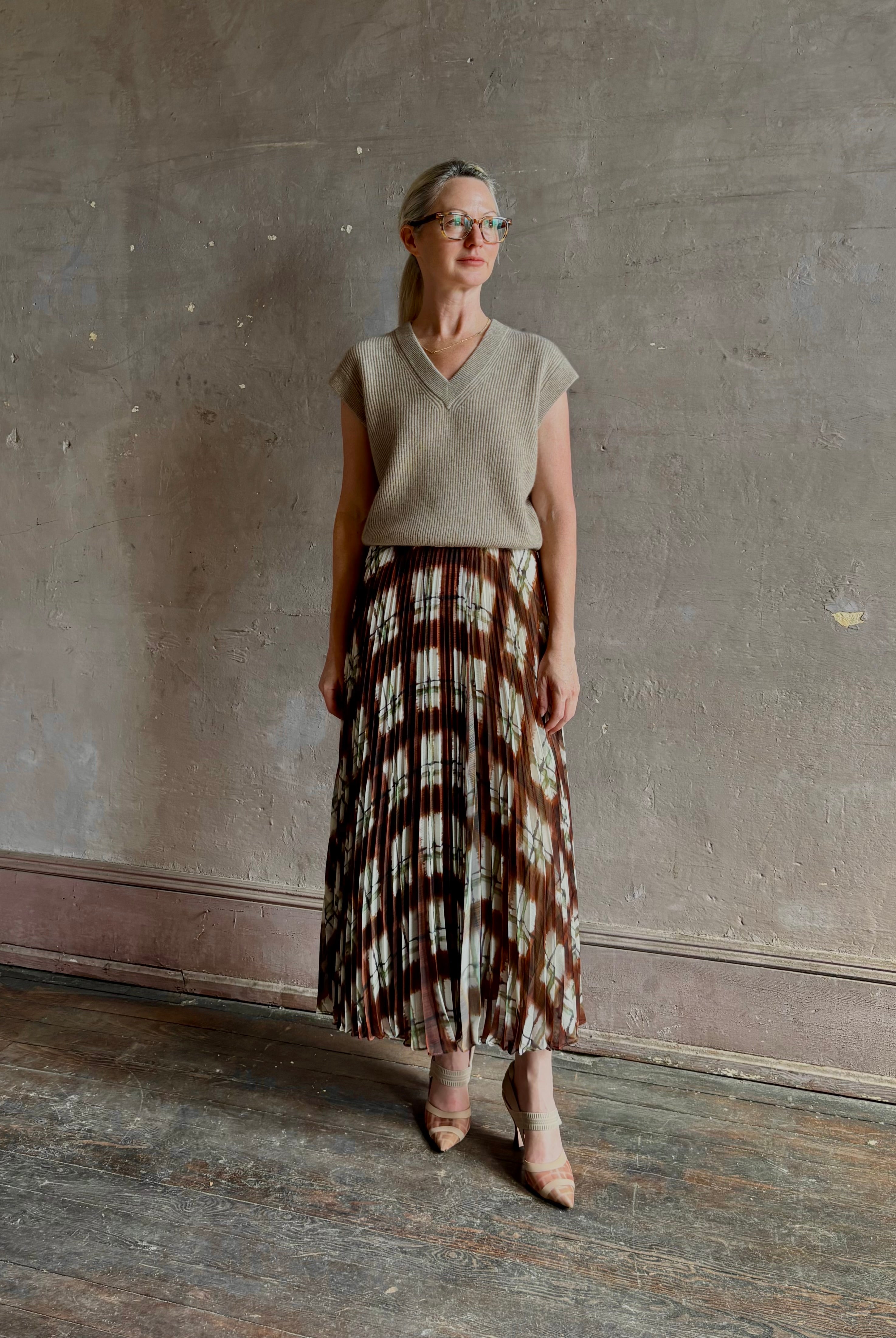 Mature woman wearing designer Cara Cara brown, cream, and green plaid patterned pleated otta maxi skirt
