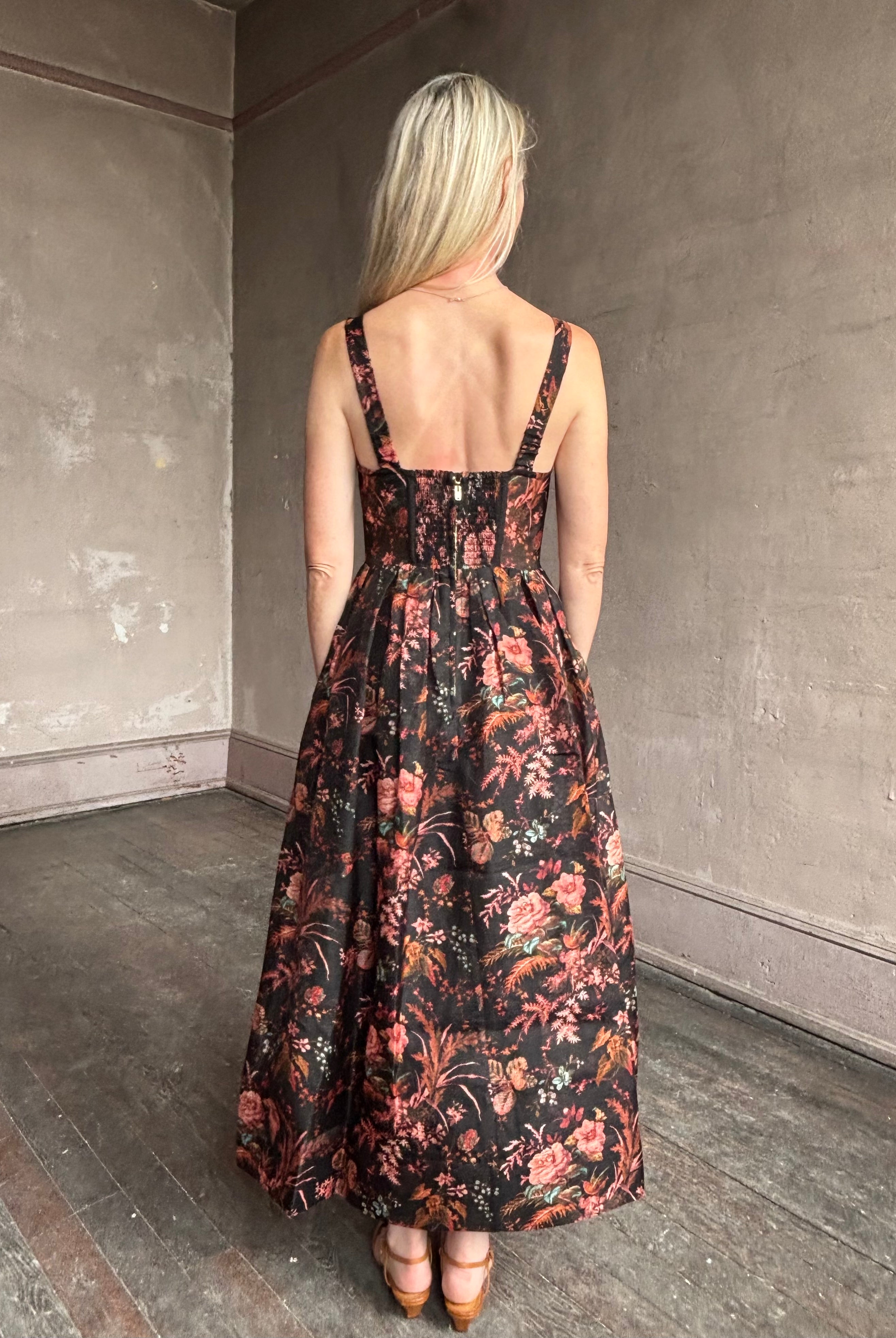 Image of woman wearing premium linen-silk Pheobe midi dress by Cara Cara with expertly crafted unlined corset bodice in an elegant black floral print