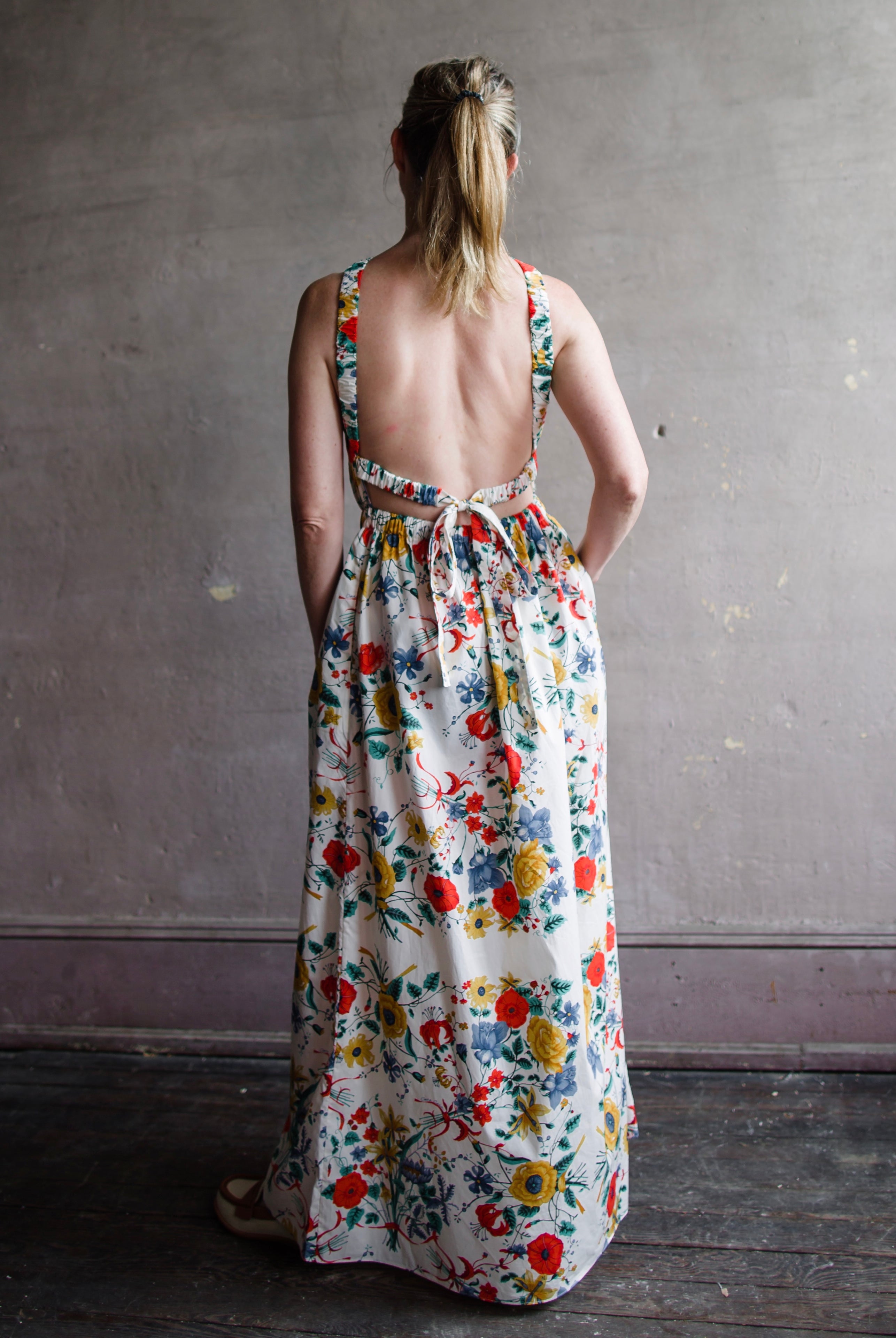 Image featuring a woman wearing the Colomba Dress from Cara Cara with a high scoop neckline and elastic waistband and open back.