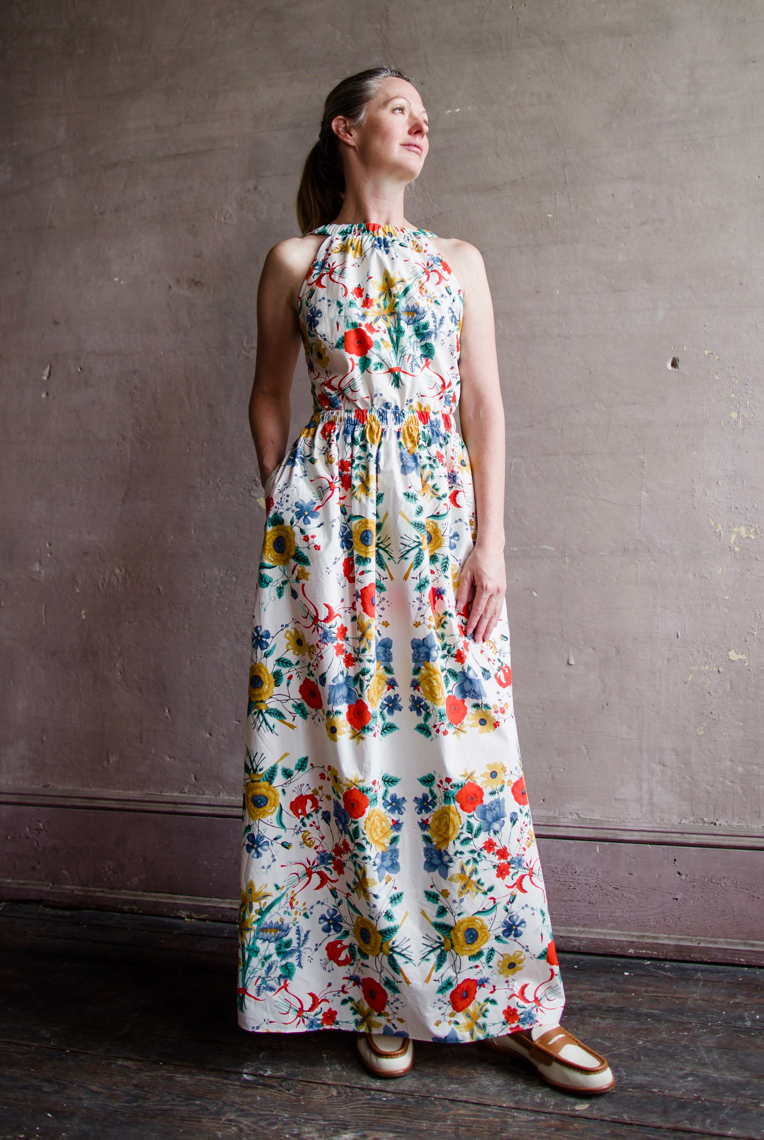 Image featuring a woman wearing the Colomba Dress from Cara Cara with a high scoop neckline and elastic waistband and open back.