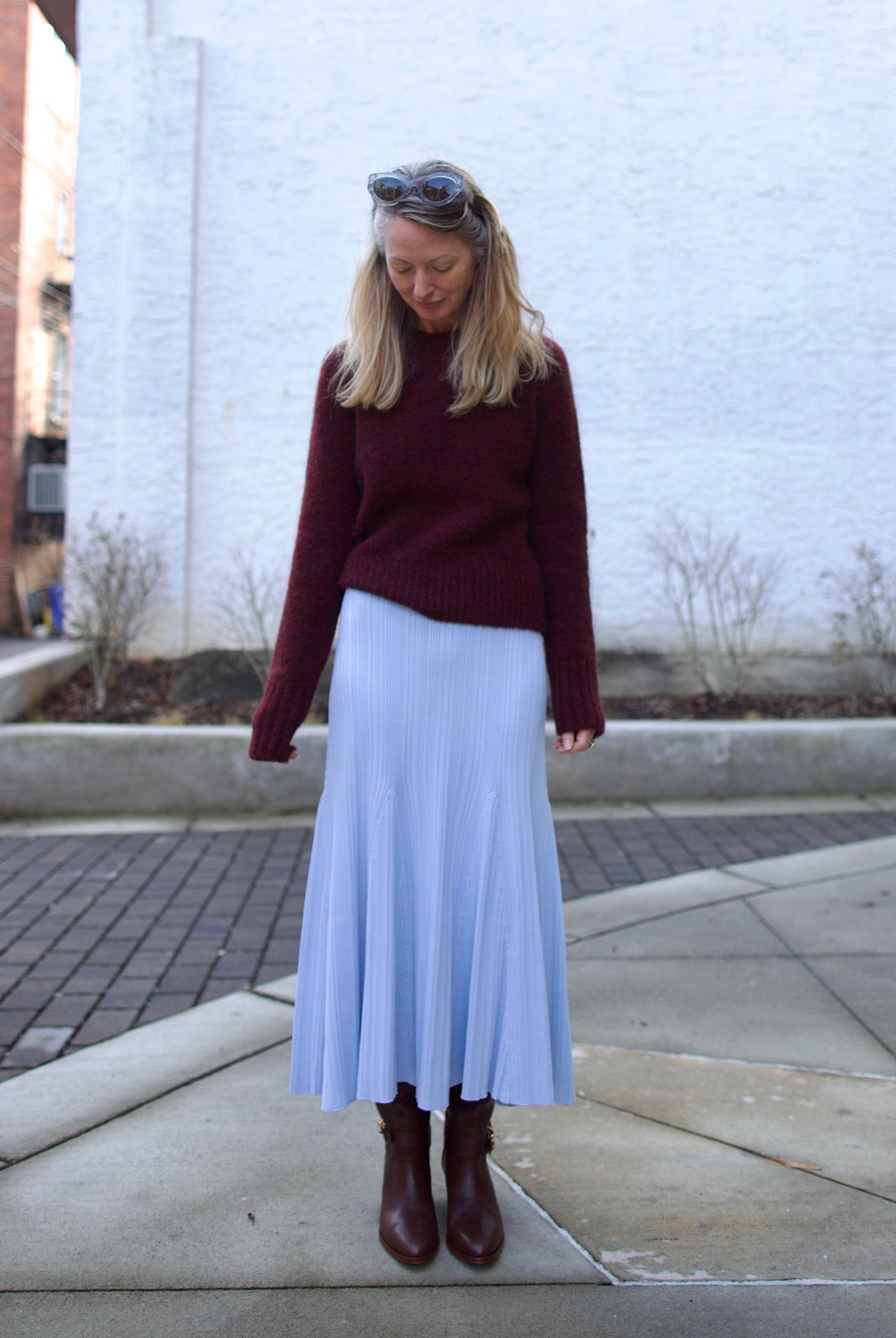 Mature woman wearing designer Cara Cara dara skirt in sky blue in flattering fit and flare sihlouette perfect layering with a heavy fall sweater