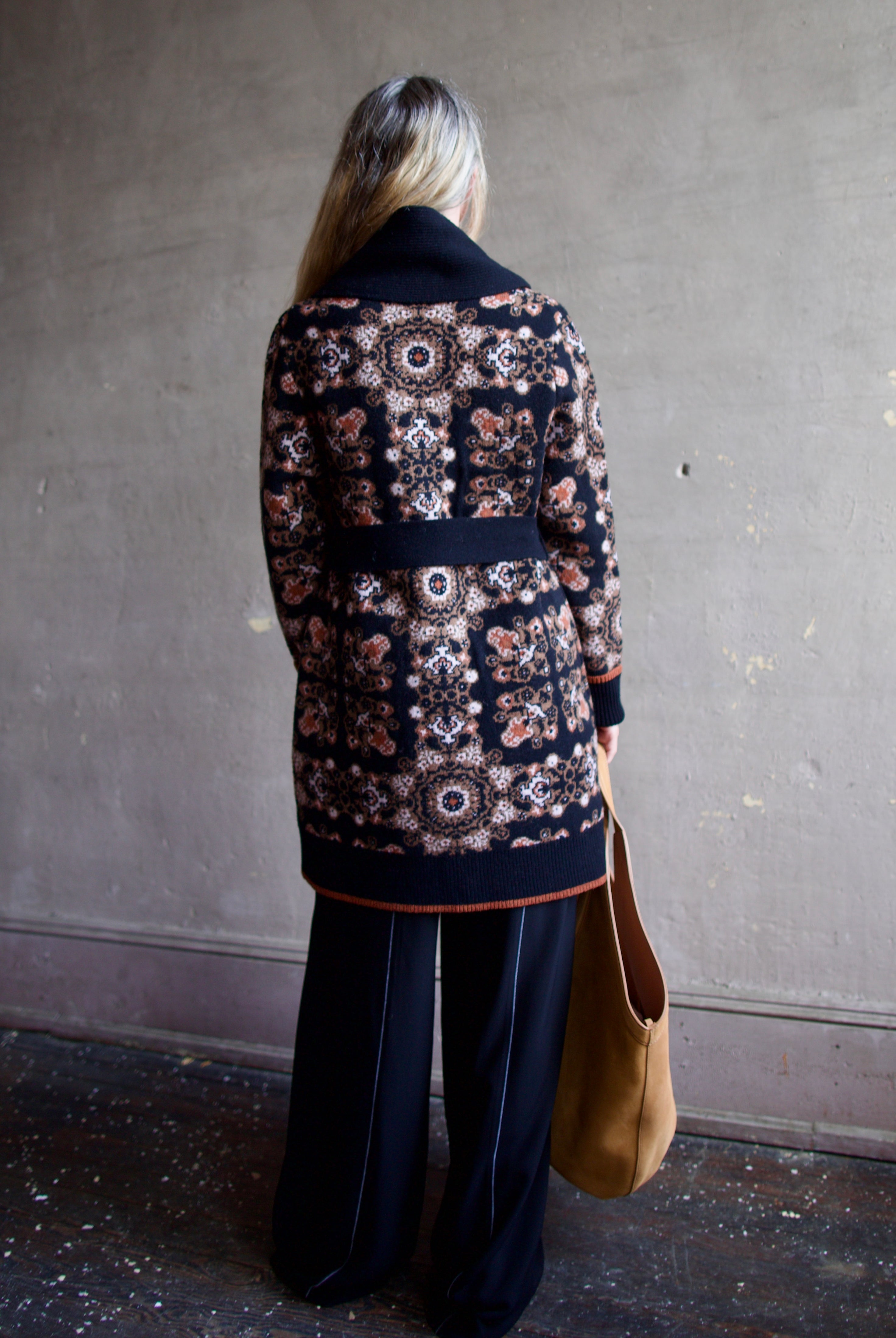 Image featuring a woman wearing the Laney cardigan by Cara Cara with ribbed collar, a tie waist, front pockets, and mid thigh length true to size fit.