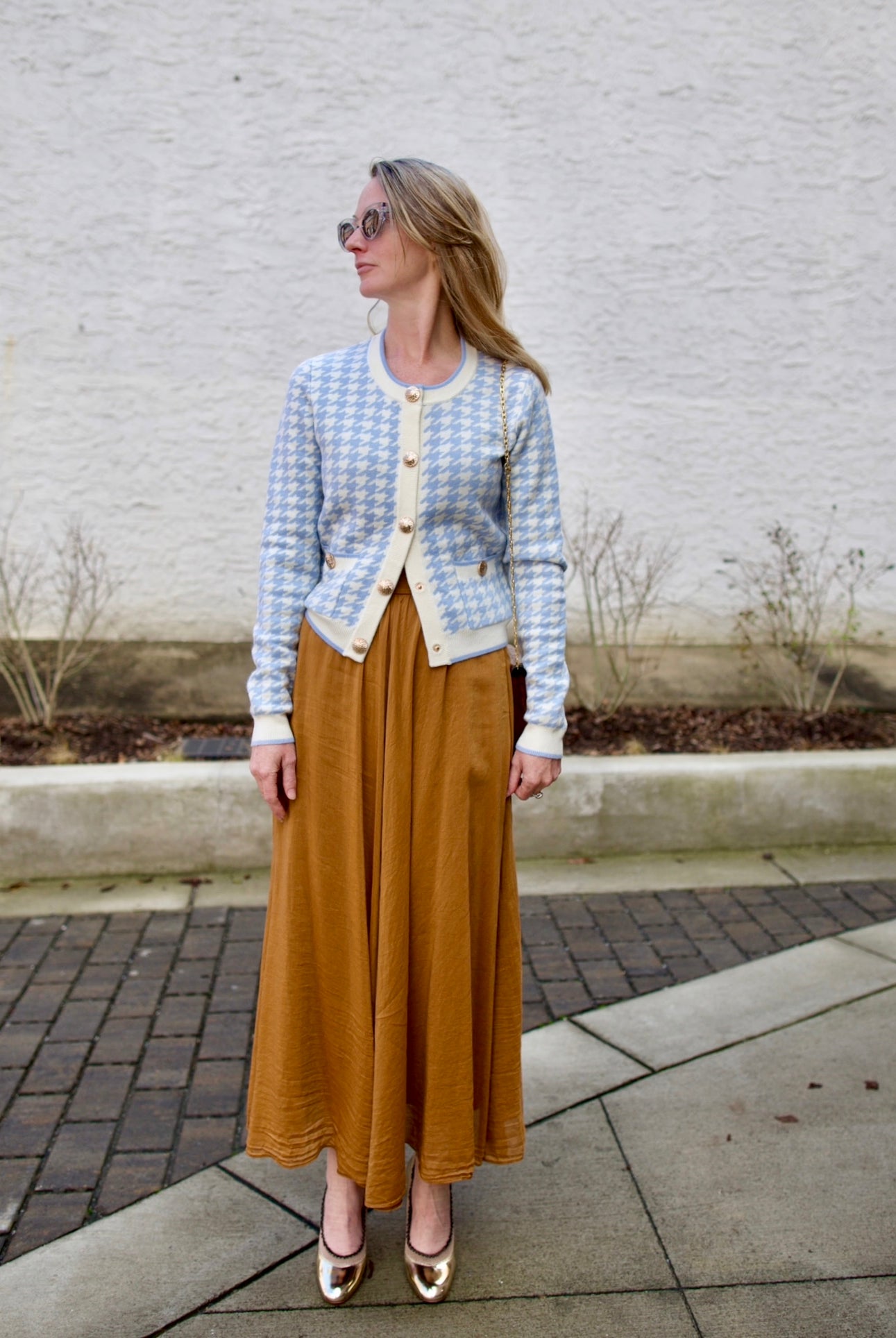 close up image of a woman wearing the Cara Cara priscilla cardigan and forte forte skirt with the Ulla Johnson ruffle pumps