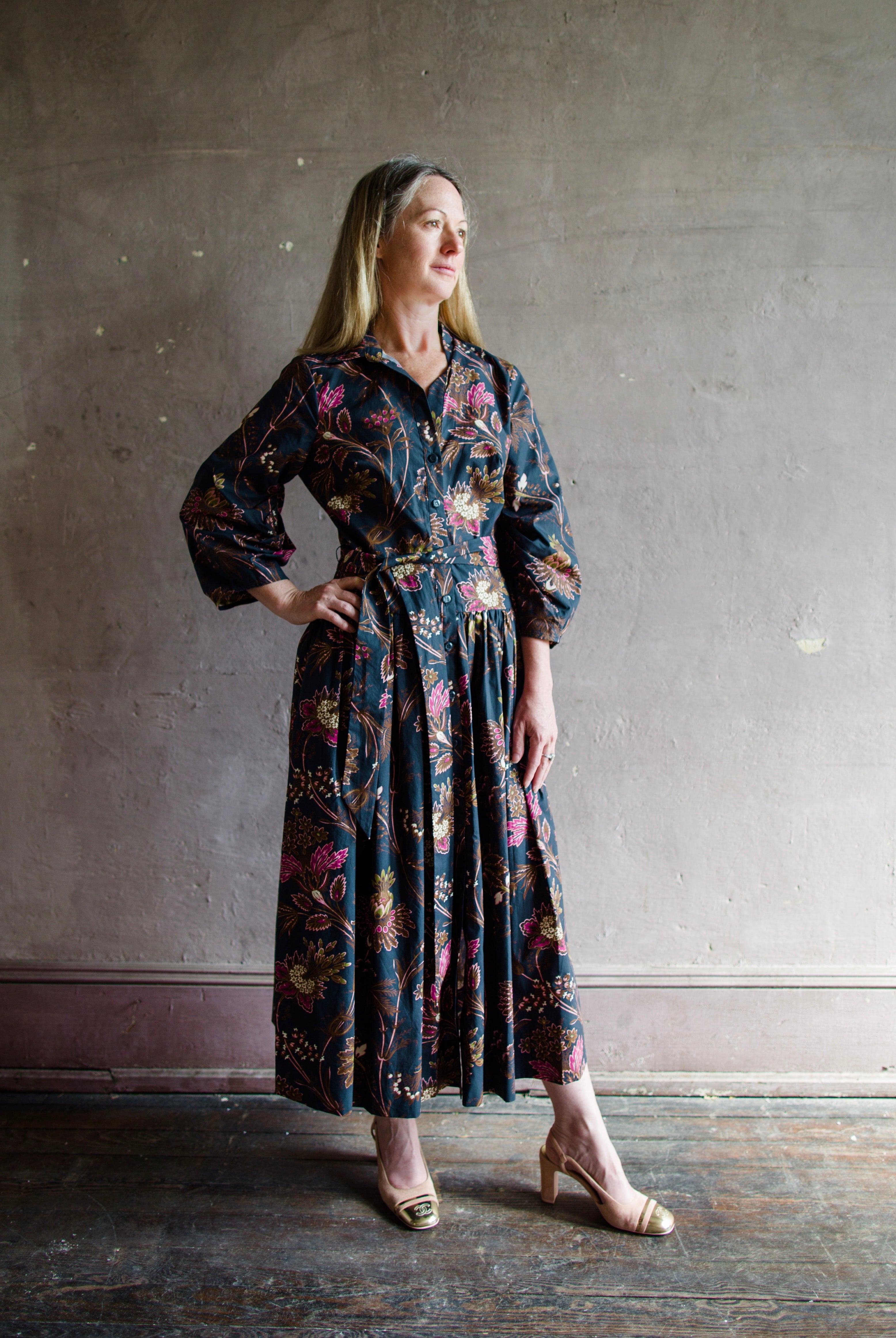 Image featuring a woman wearing the cotton Raya dress by Cara Cara with a collar and button front with full sleeves and flowy skirting in Blue Vintage Blossom print.