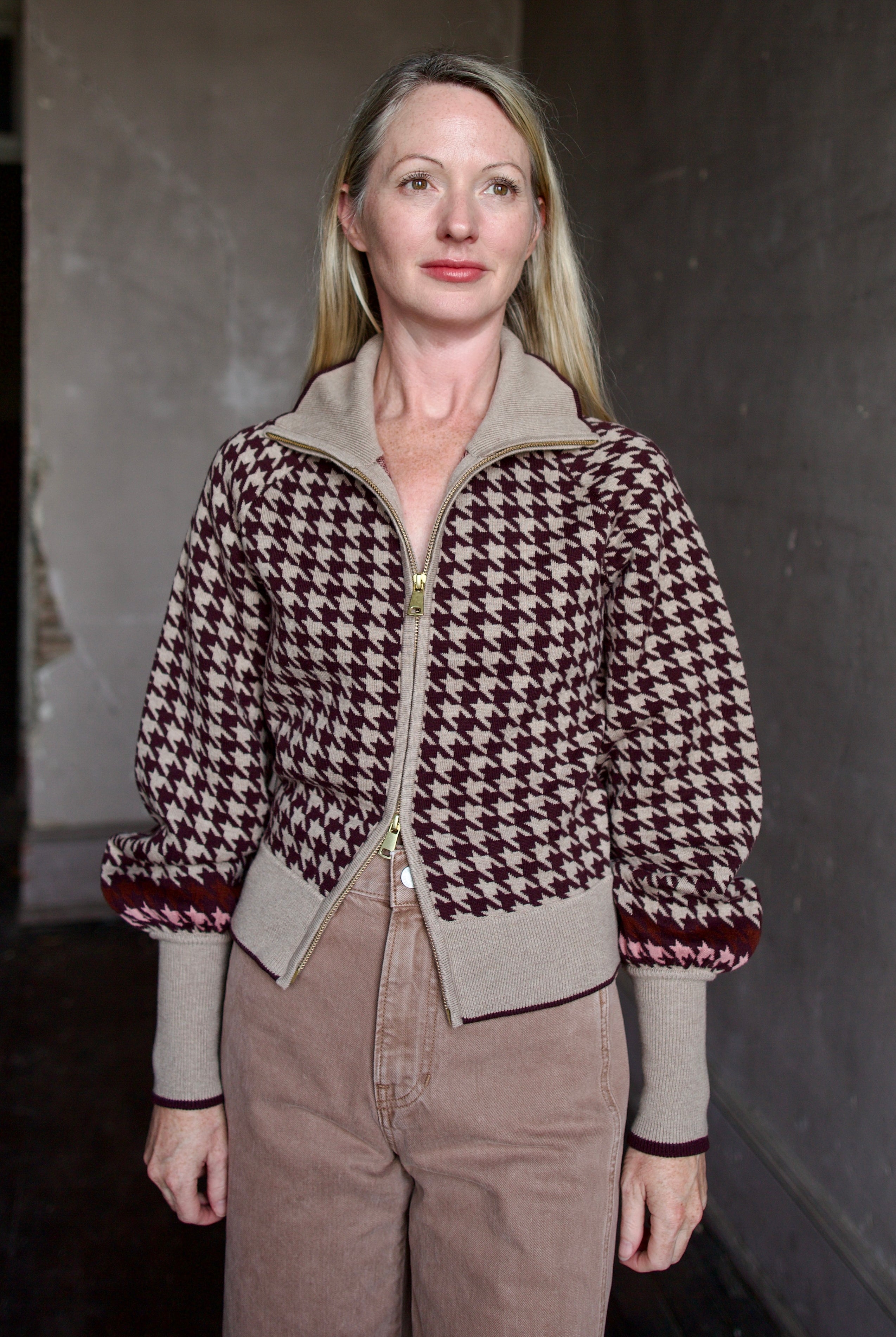 Model wearing a houndstooth patterned fine merino wool Lyss zip up layering sweater by Cara Cara