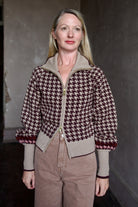 Model wearing a houndstooth patterned fine merino wool Lyss zip up layering sweater by Cara Cara