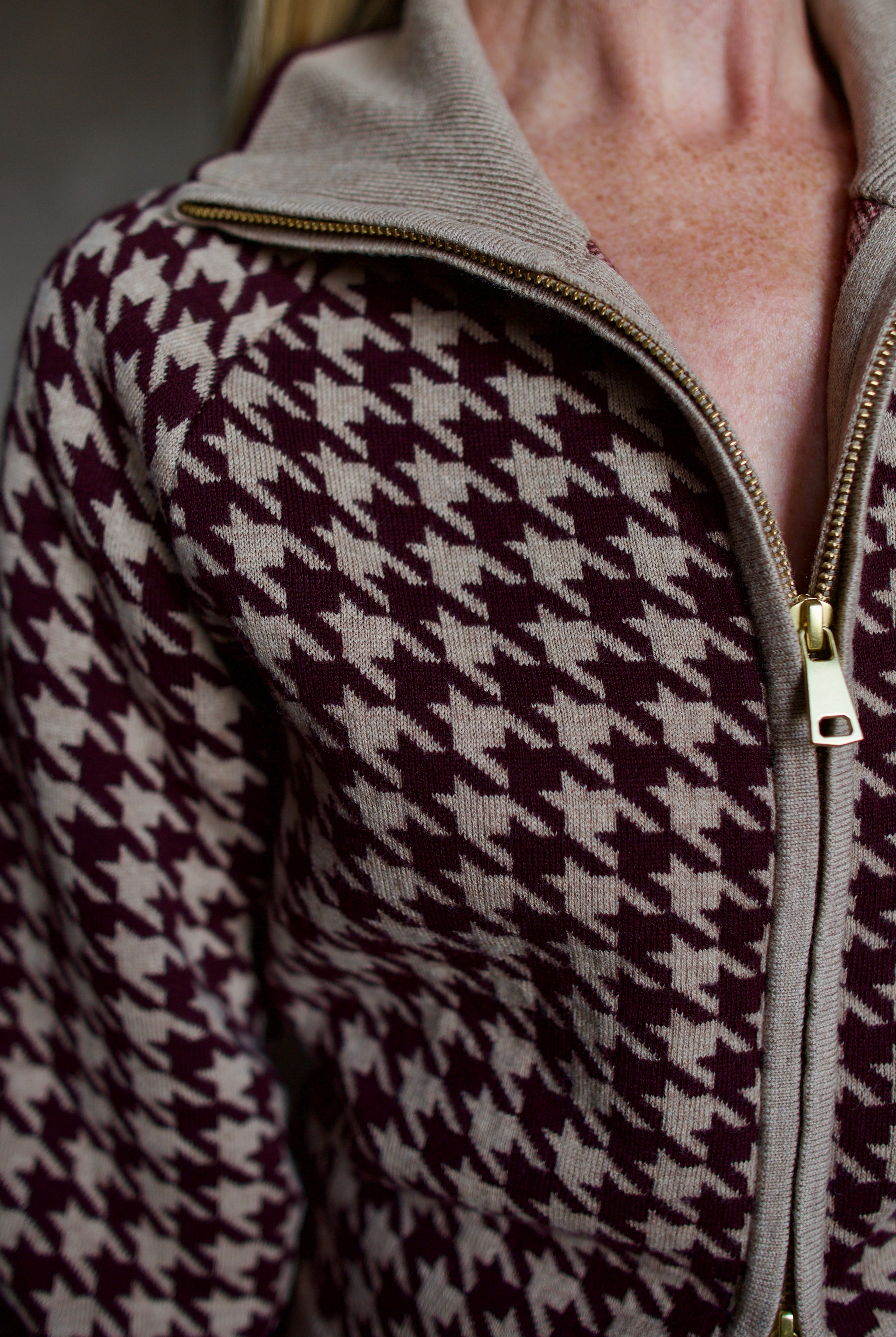 Model wearing a houndstooth patterned fine merino wool Lyss zip up layering sweater by Cara Cara