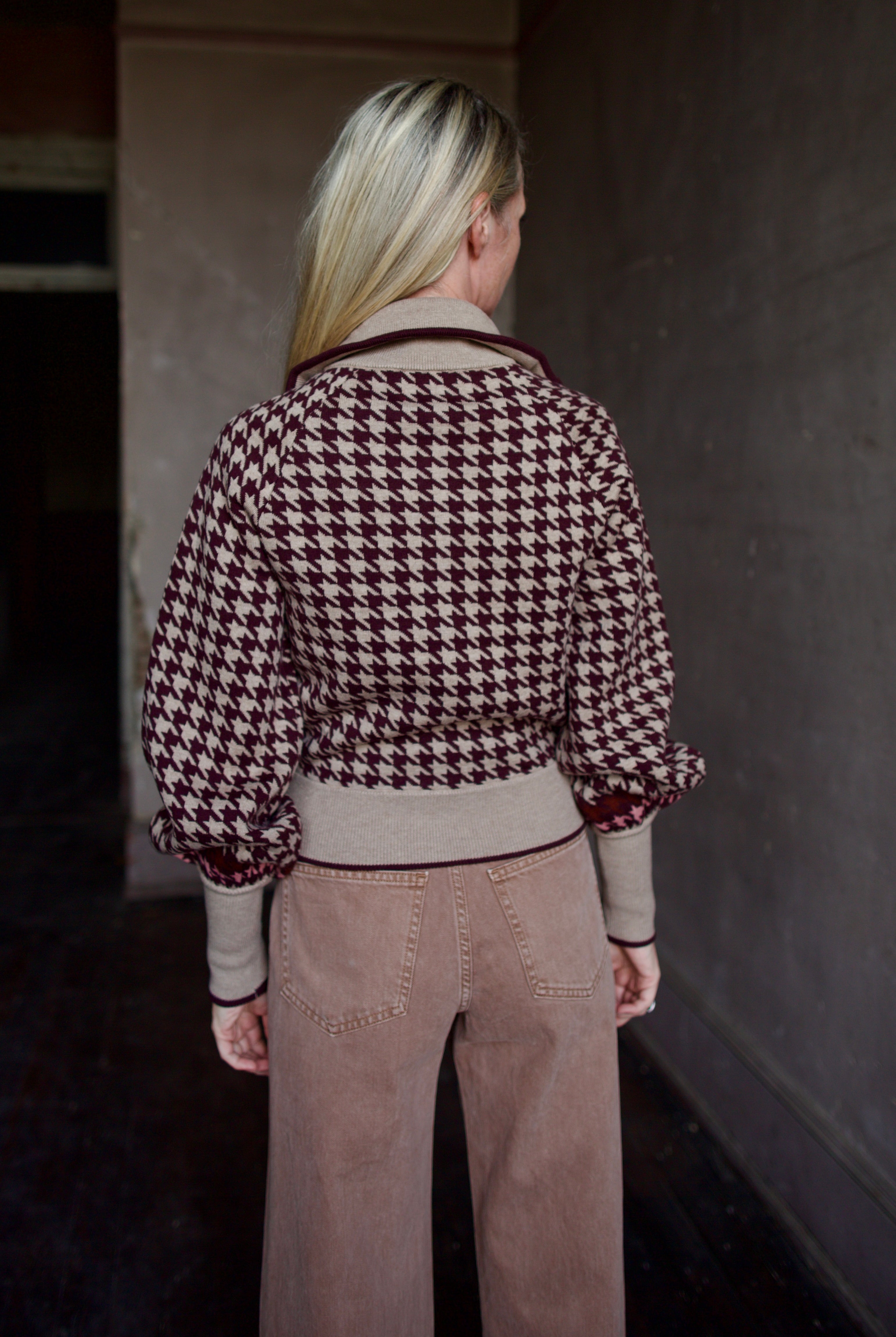 Model wearing a houndstooth patterned fine merino wool Lyss zip up layering sweater by Cara Cara