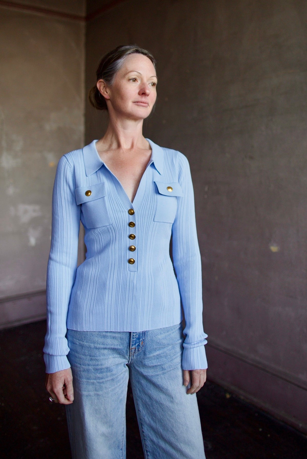 Mature woman wearing Cara Cara Belleport Top in Sky Blue premium viscose-blend ribbed texture button front closure, flap pockets gold buttonslong sleeves