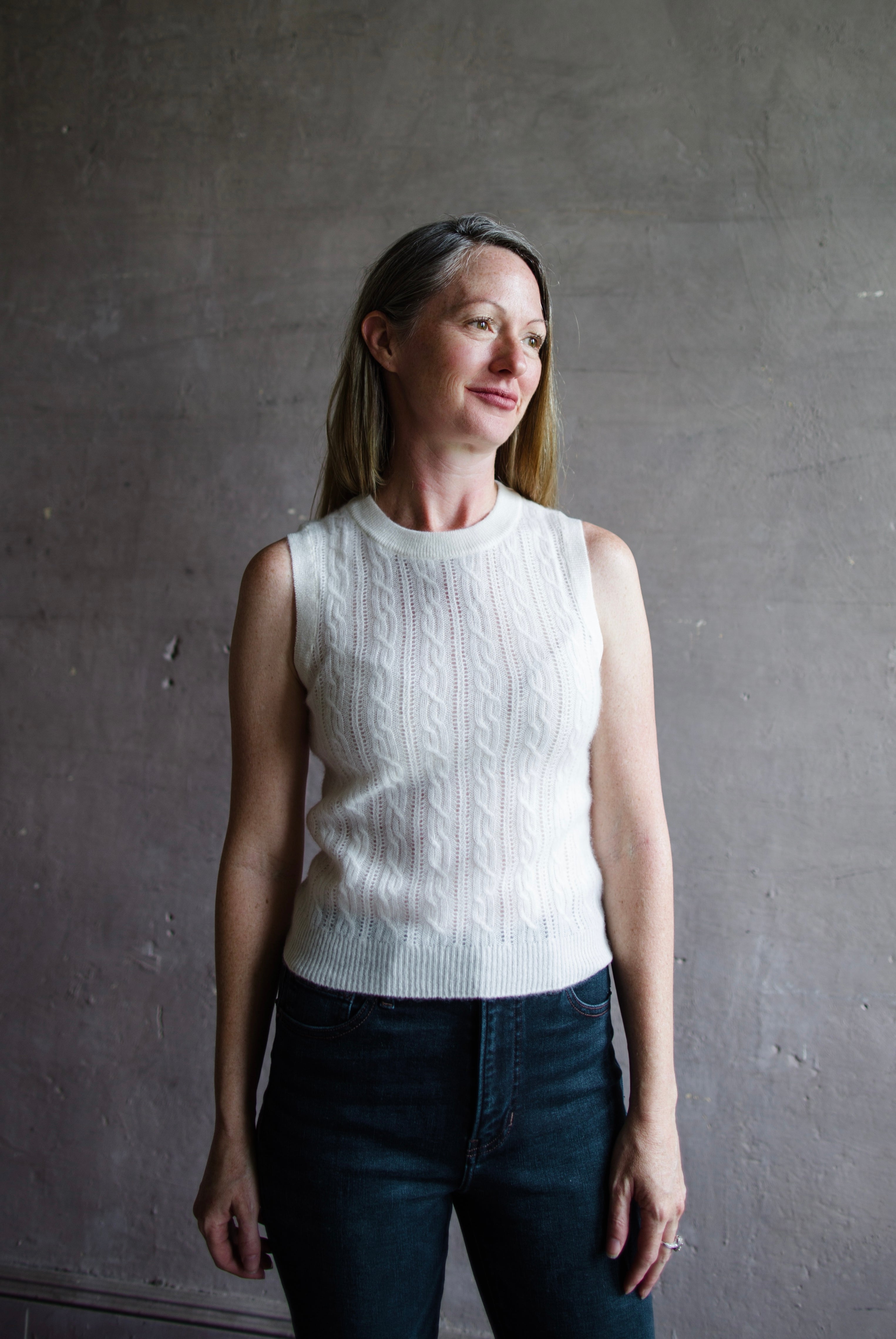 Image featuring a woman wearing a cream sweater by Naadam with a crew neckline and soft cable knit texture in a slightly tailored fit.