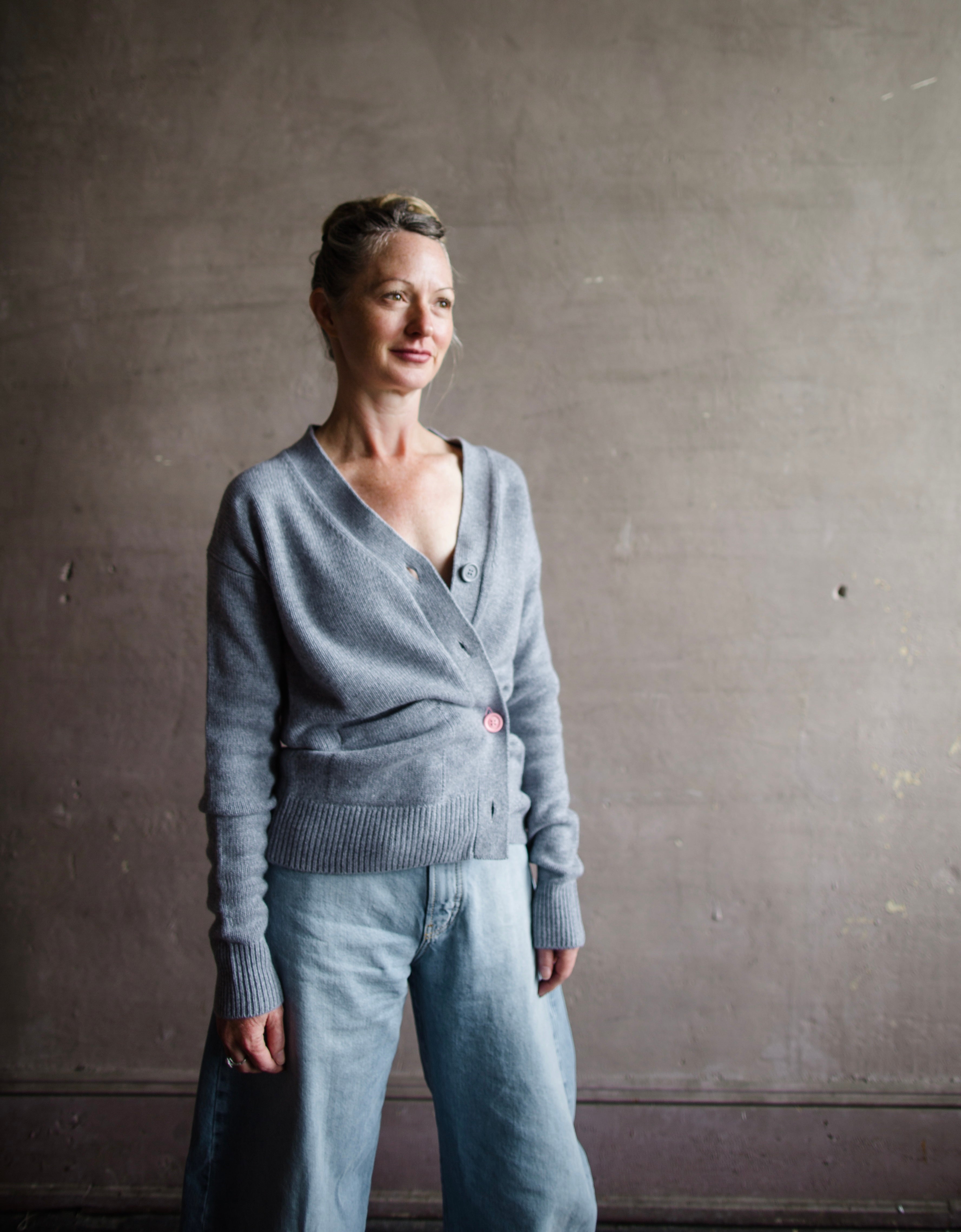 Image featuring a woman wearing the grey cashmere sweater by Cissa with a button front than can be worn multiple ways- crossed over or as a cardigan.