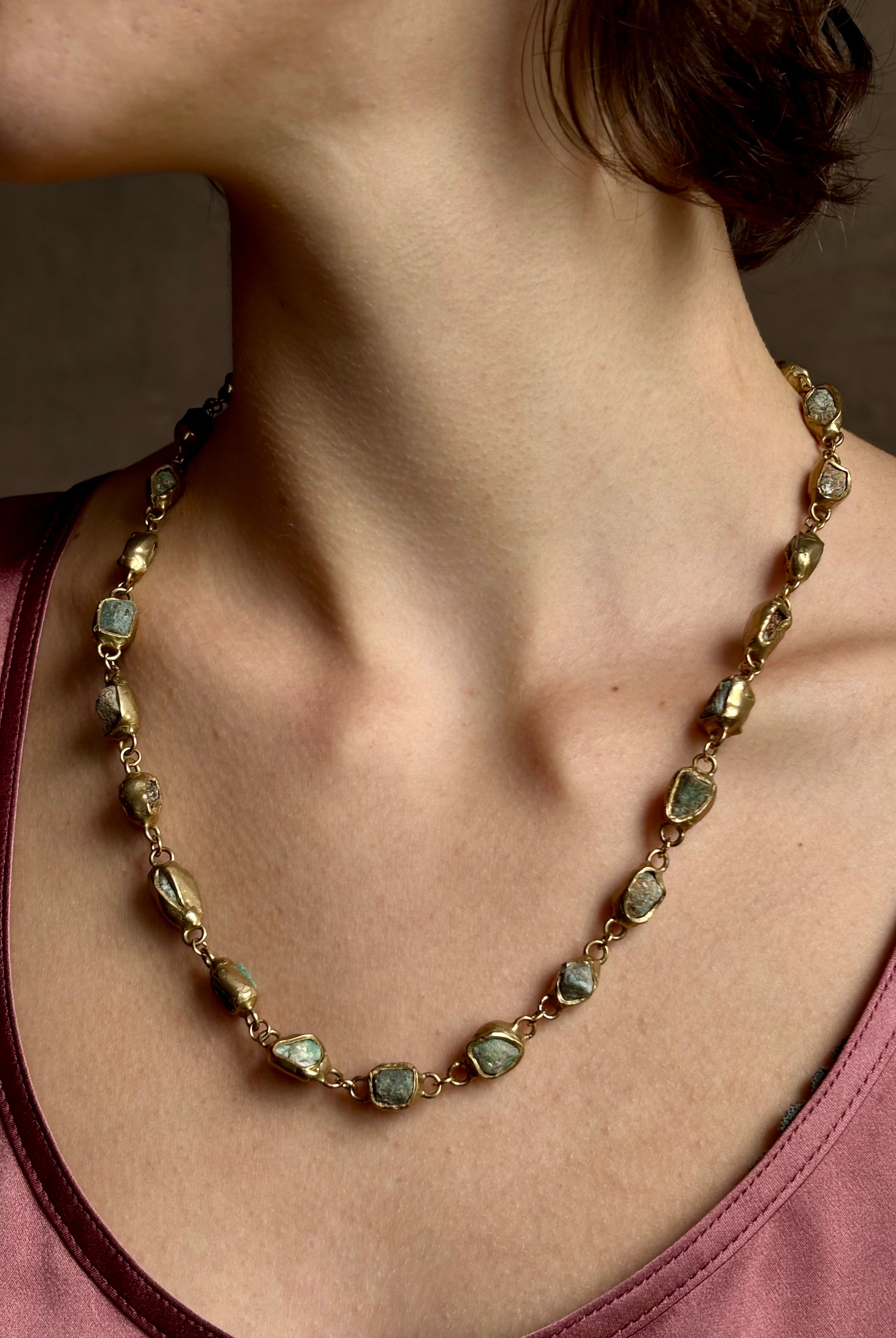 Woman wearing Guardian Path Necklace from jewelry designer Emilie Shapiro with posts on Natural emeralds individually embedded in warm brass along a clean, linear path for a beautiful statement piece handcrafted in USA