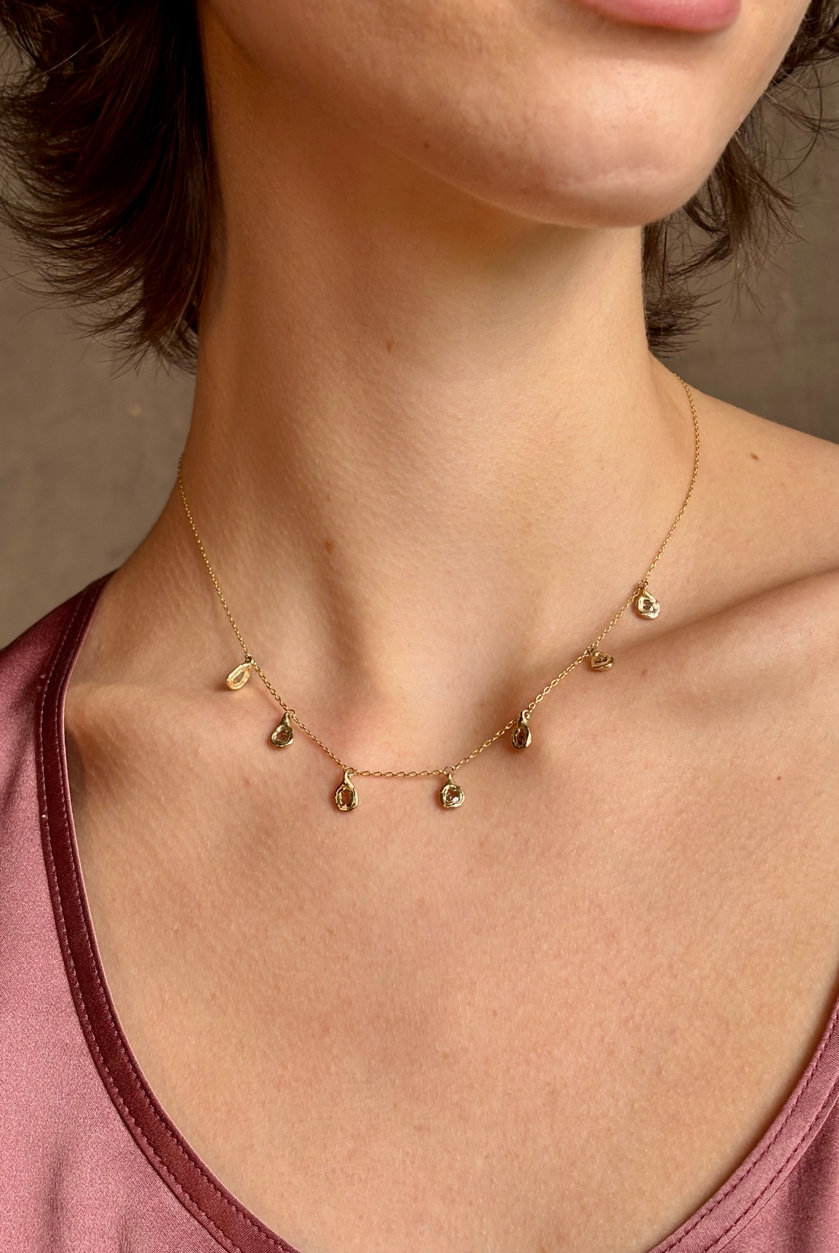 Woman wearing Mirage Cascade Diamond Necklace from New York fine jewelry designer Emilie Shapiro featuring seven dangling rose cut diamonds in 14k yellow gold exquisitely handcrafted in USA