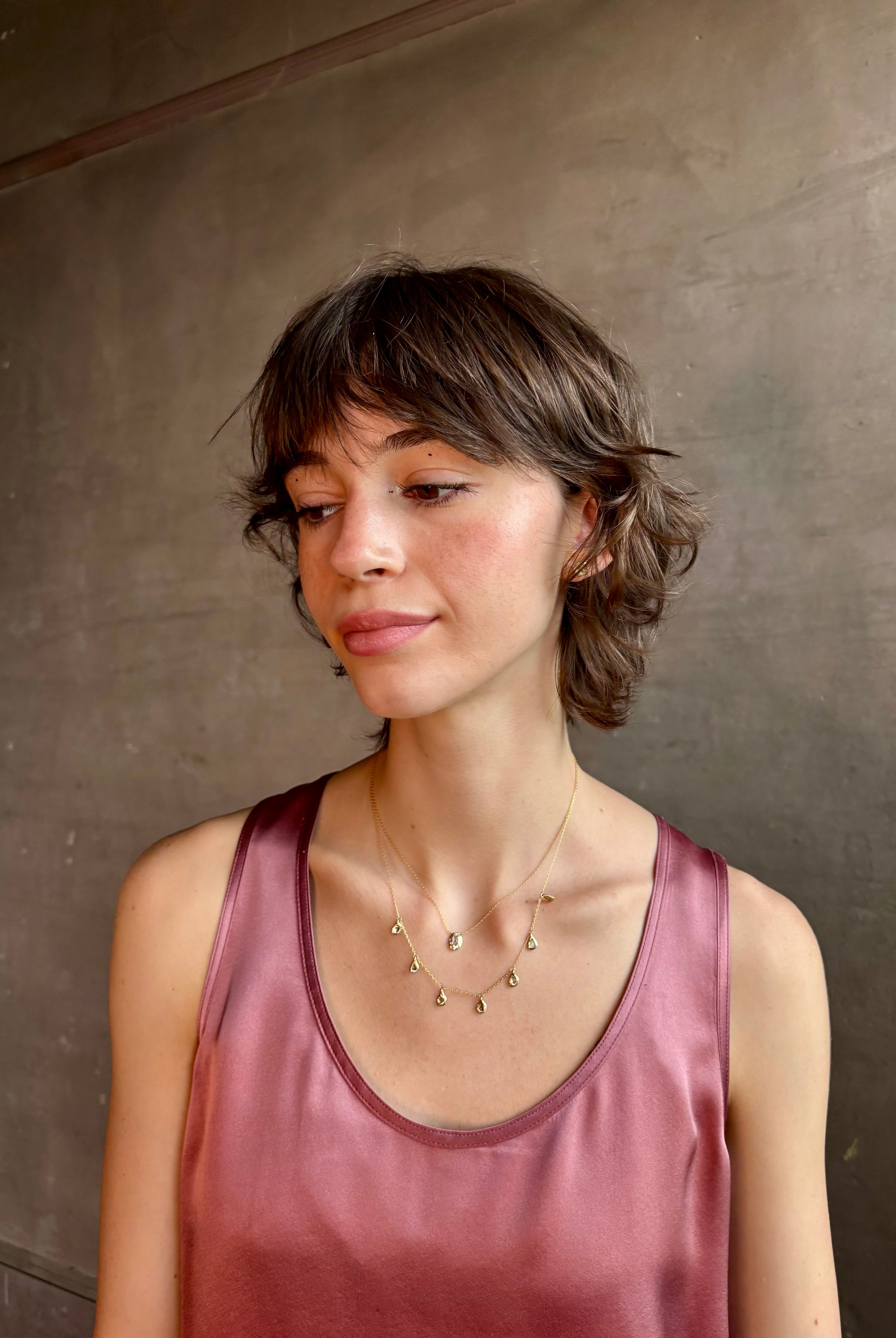 Woman wearing Mirage Cascade Diamond Necklace from New York fine jewelry designer Emilie Shapiro featuring seven dangling rose cut diamonds in 14k yellow gold exquisitely handcrafted in USA