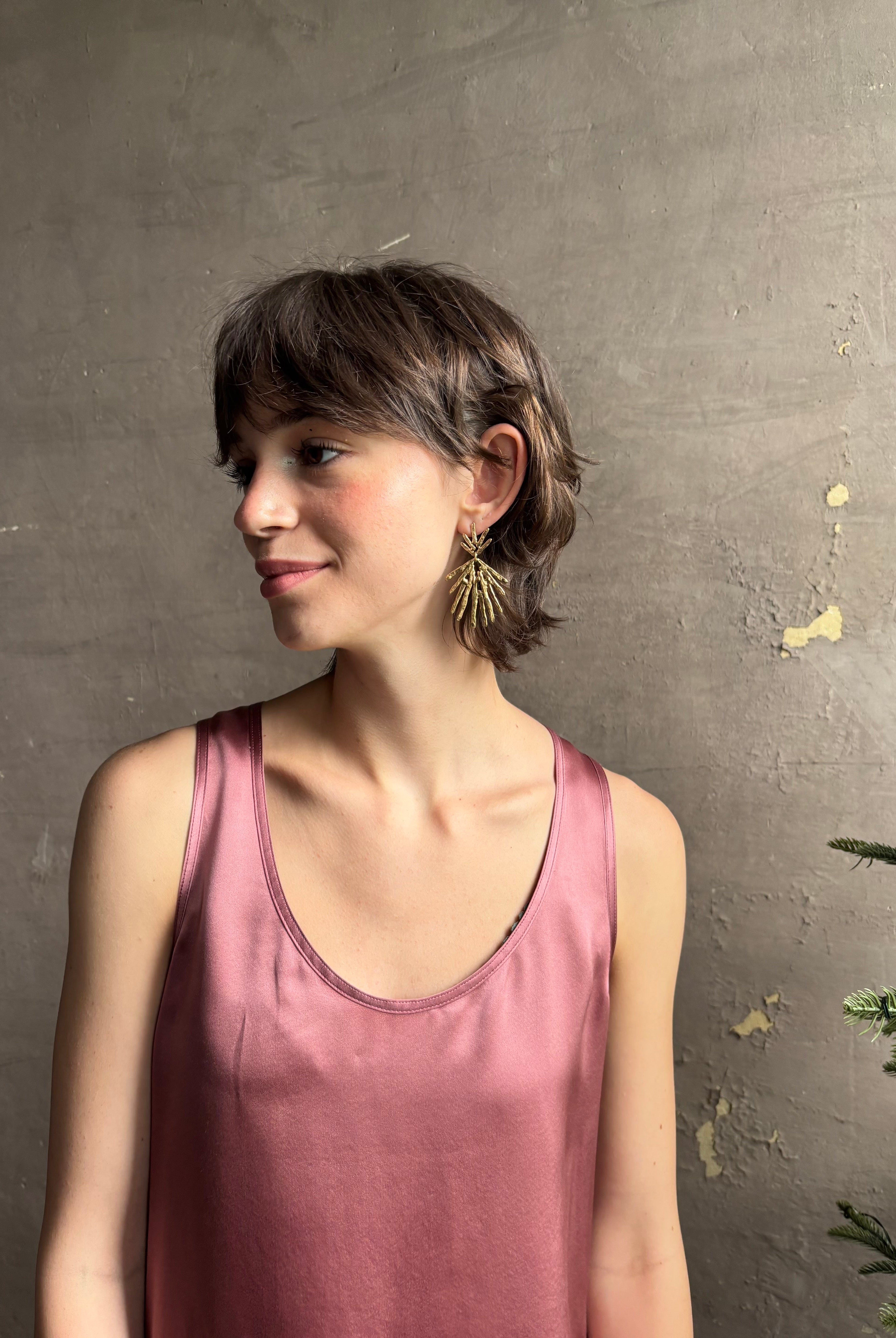 Woman wearing Solaris post Earrings from New York fine jewelry artist Emilie Shapiro that channels the radiant, life-giving energy of the sun in an exquisitely handcrafted textured brass form. Large, statement-making and thoroughly wearable dangle earrings