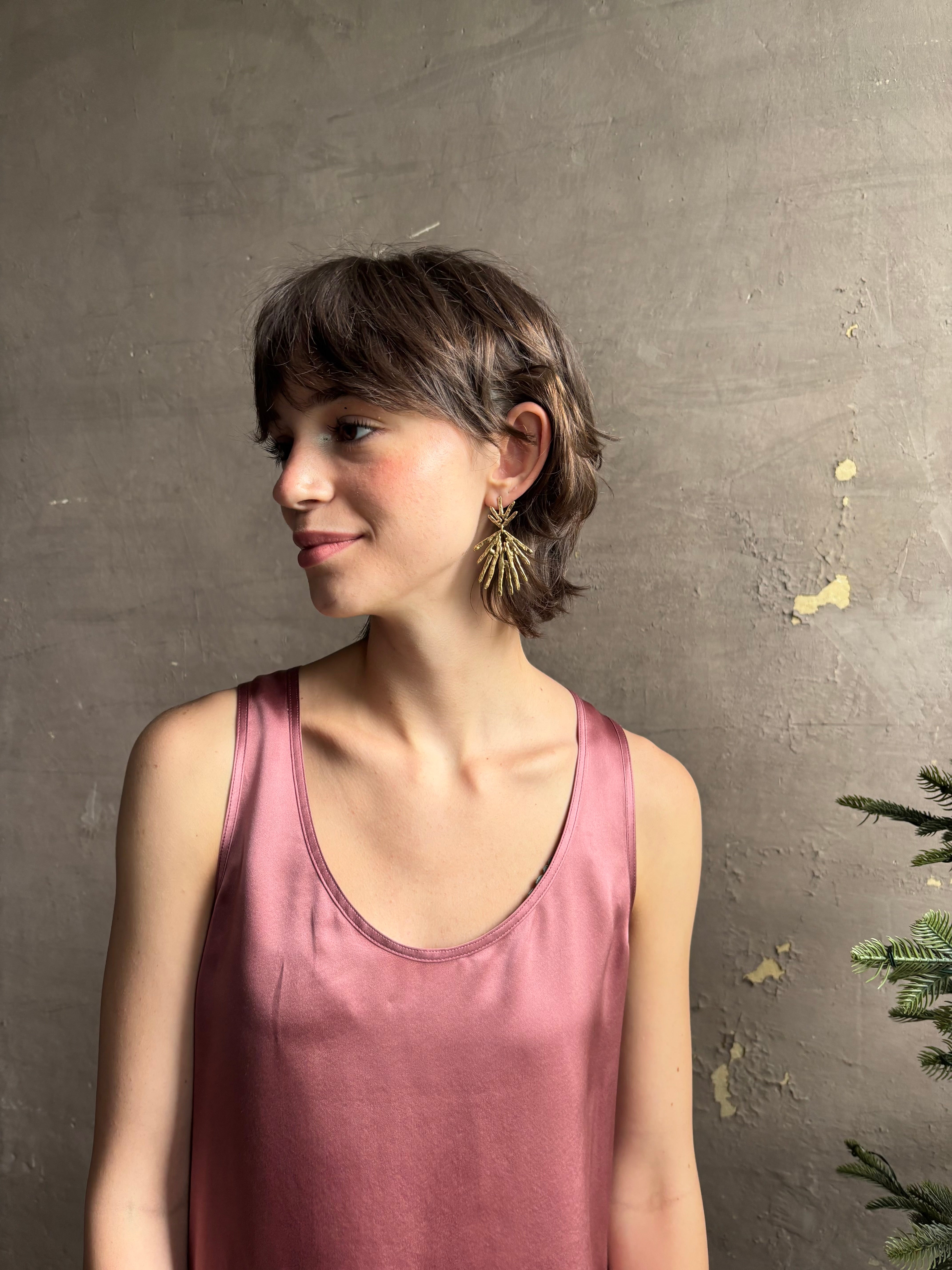 Woman wearing Solaris post Earrings from New York fine jewelry artist Emilie Shapiro that channels the radiant, life-giving energy of the sun in an exquisitely handcrafted textured brass form. Large, statement-making and thoroughly wearable dangle earrings
