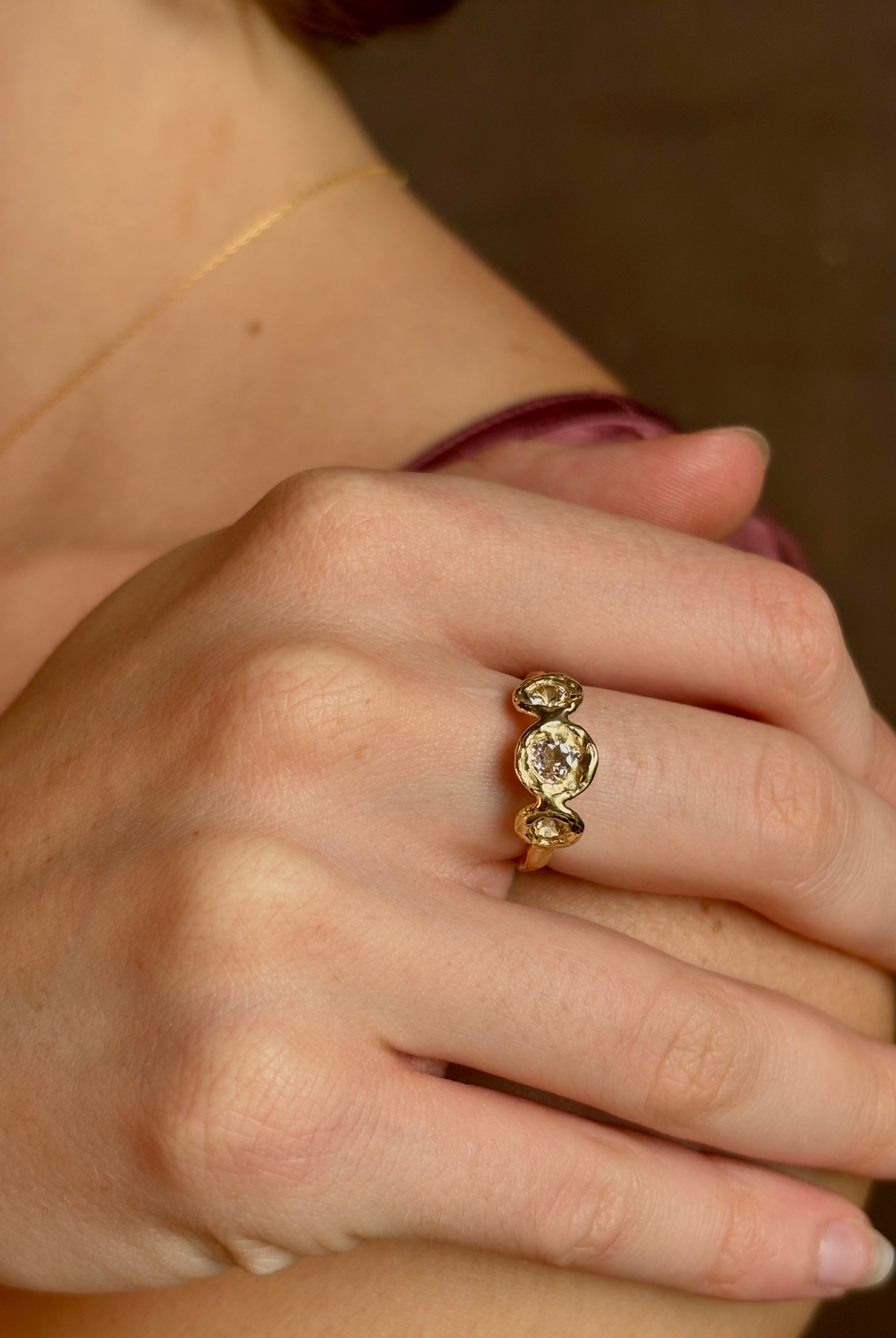 Woman wearing a White Sapphire statement Ring from contemporary fine jewelry designer Emilie Shapiro composed of three round white sapphires set in 14k yellow gold handcrafted in USA