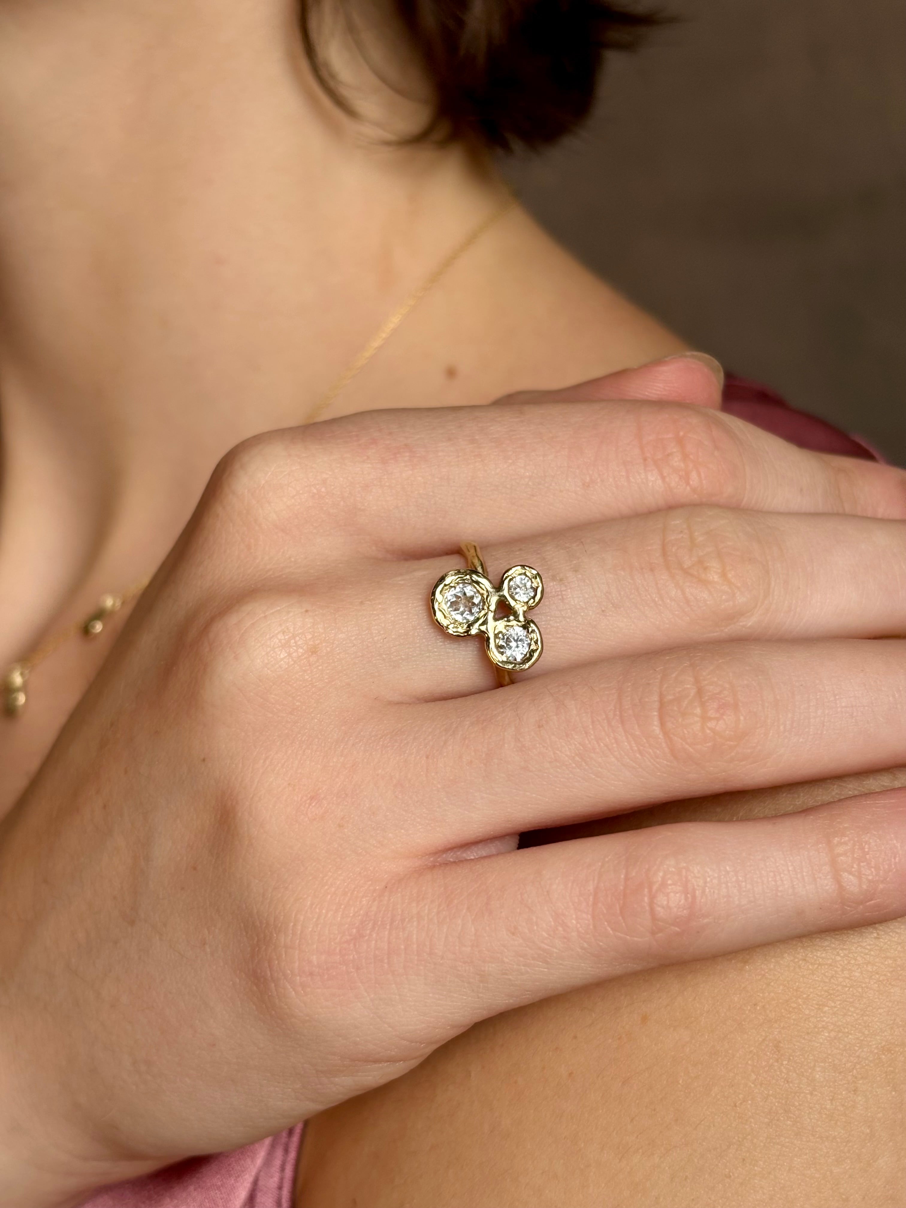 Woman wearing a White Sapphire statement Ring from contemporary fine jewelry designer Emilie Shapiro composed of three round white sapphires set in 14k yellow gold handcrafted in USA