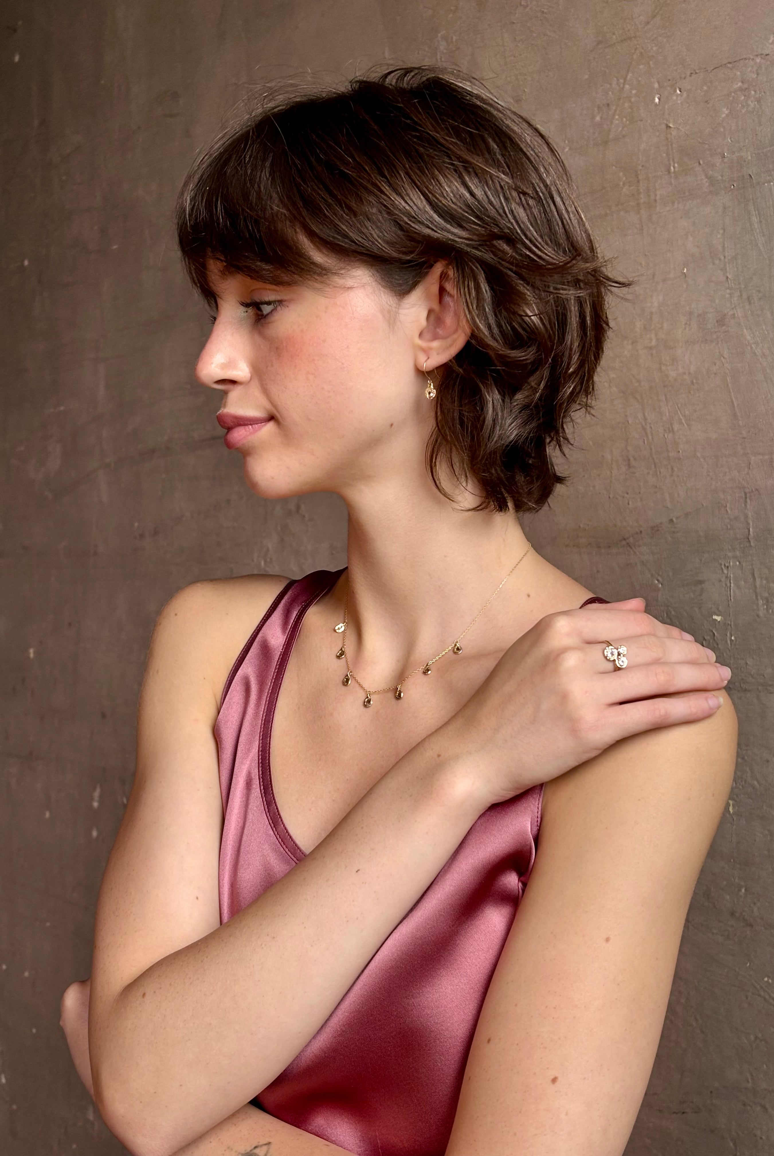 Woman wearing a White Sapphire statement Ring from contemporary fine jewelry designer Emilie Shapiro composed of three round white sapphires set in 14k yellow gold handcrafted in USA