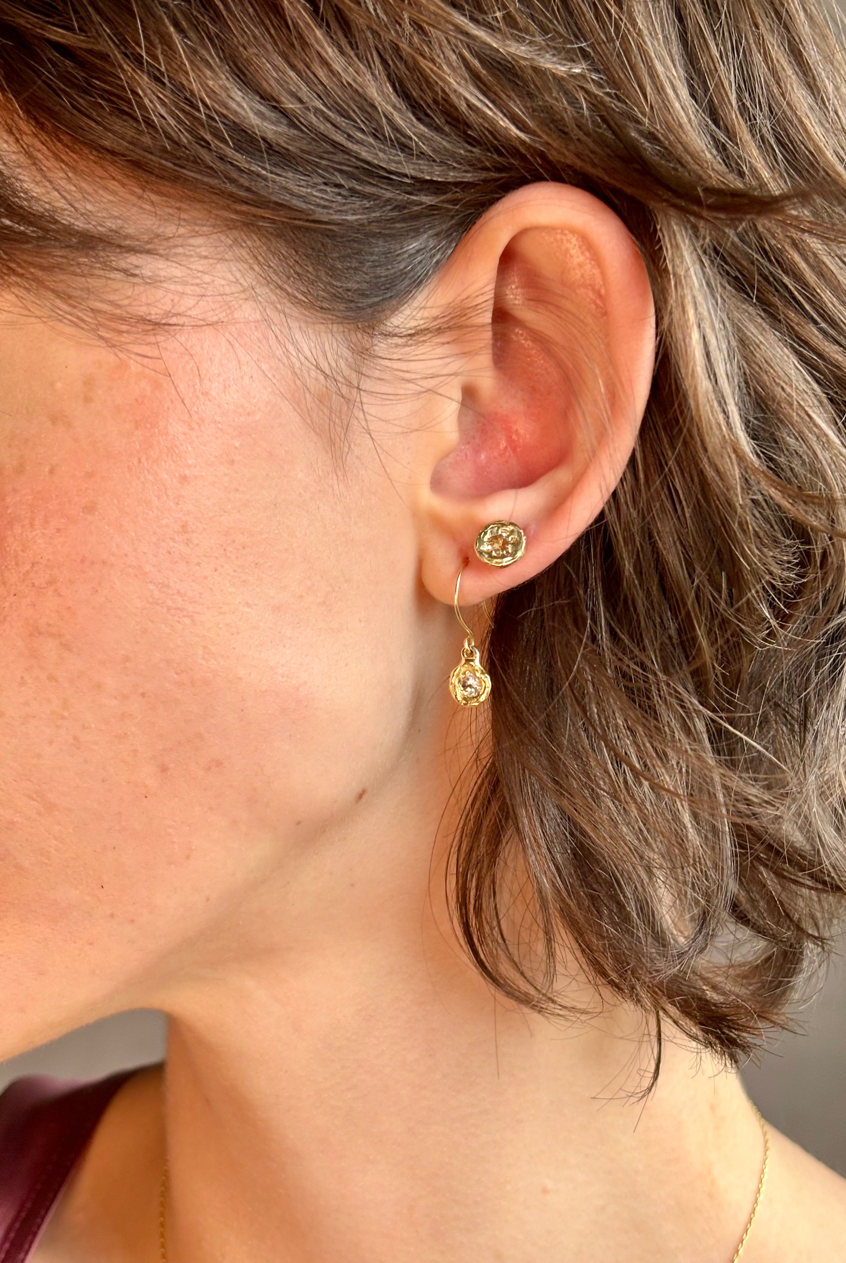 Woman wearing white Sapphire drop earrings from contemporary fine jewelry designer Emilie Shapiro composed of a single round white sapphires set in 14k yellow gold handcrafted in USA