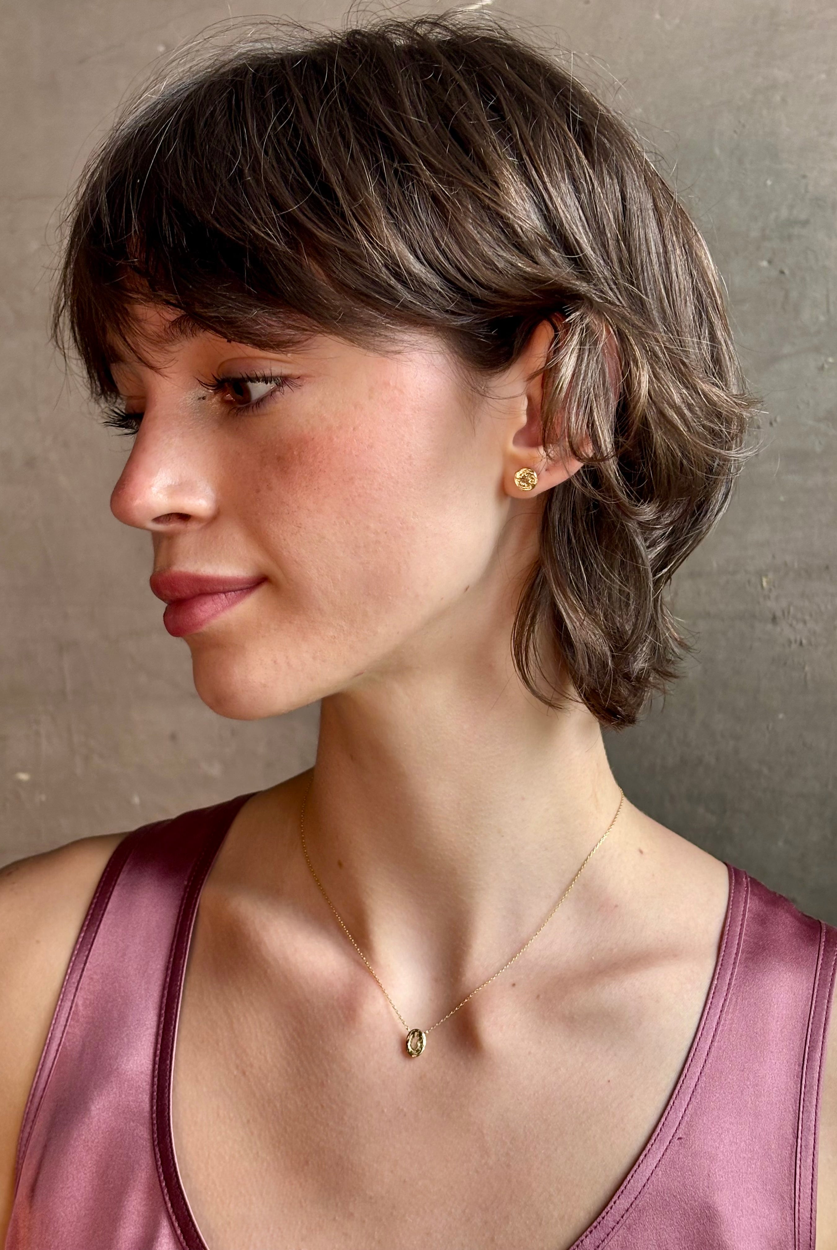 Woman wearing white Sapphire stud earrings from contemporary fine jewelry designer Emilie Shapiro composed of a single round white sapphires set in 14k yellow gold handcrafted in USA