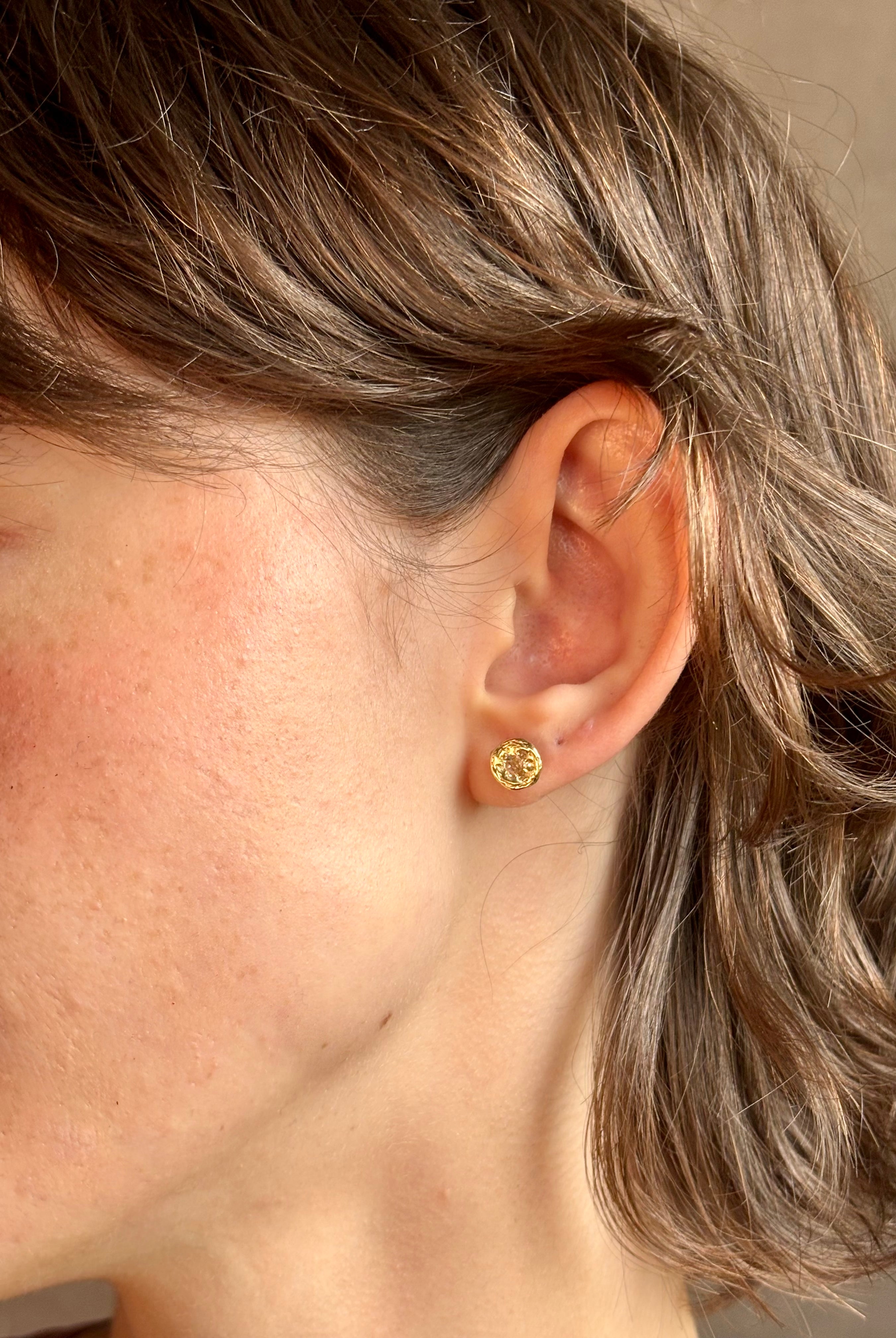 Woman wearing white Sapphire stud earrings from contemporary fine jewelry designer Emilie Shapiro composed of a single round white sapphires set in 14k yellow gold handcrafted in USA