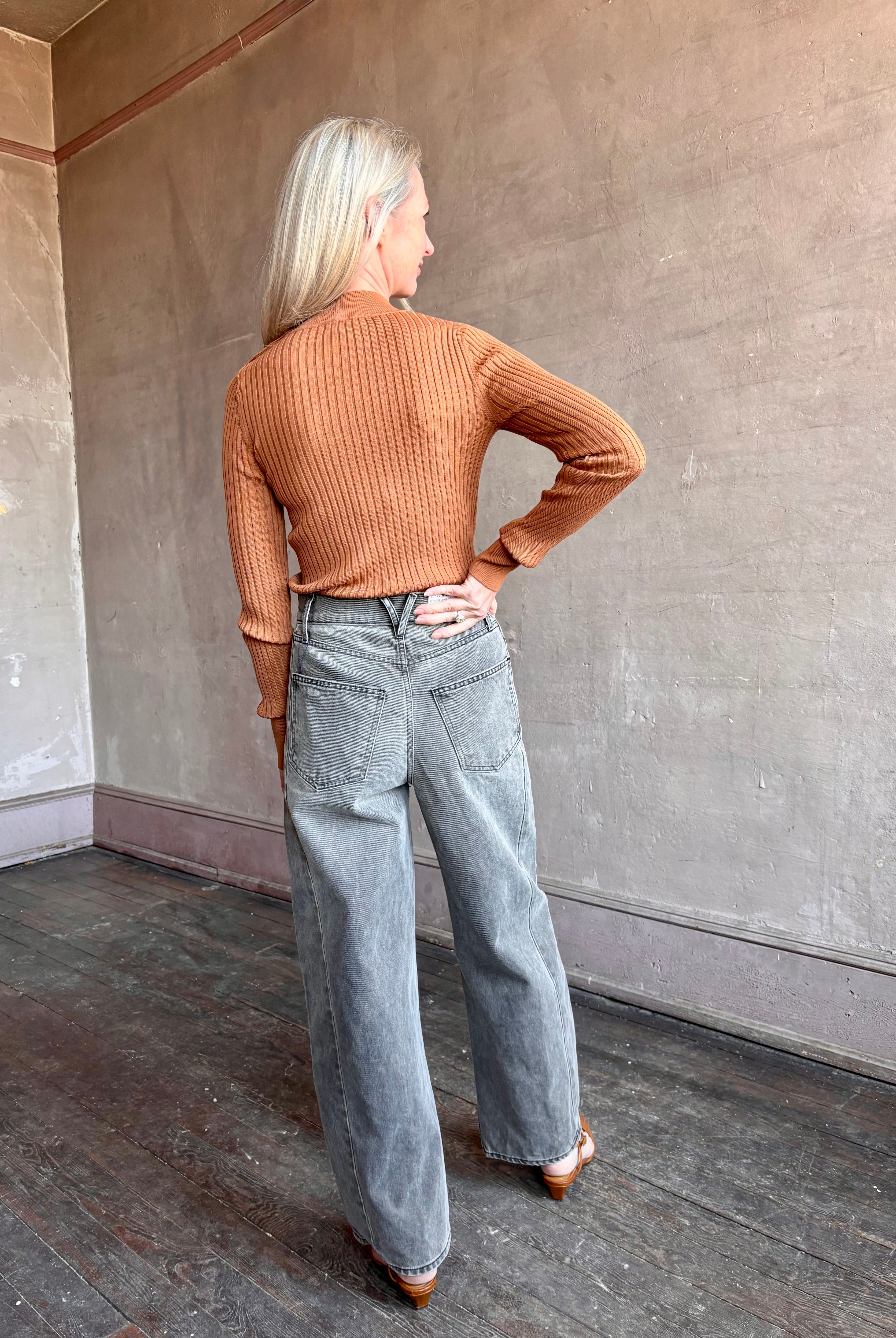 Image of woman wearing luxury Italian Forte Forte Superfine Merino Ribbed Turtleneck Sweater in neutral carmel colorway with long sleeves