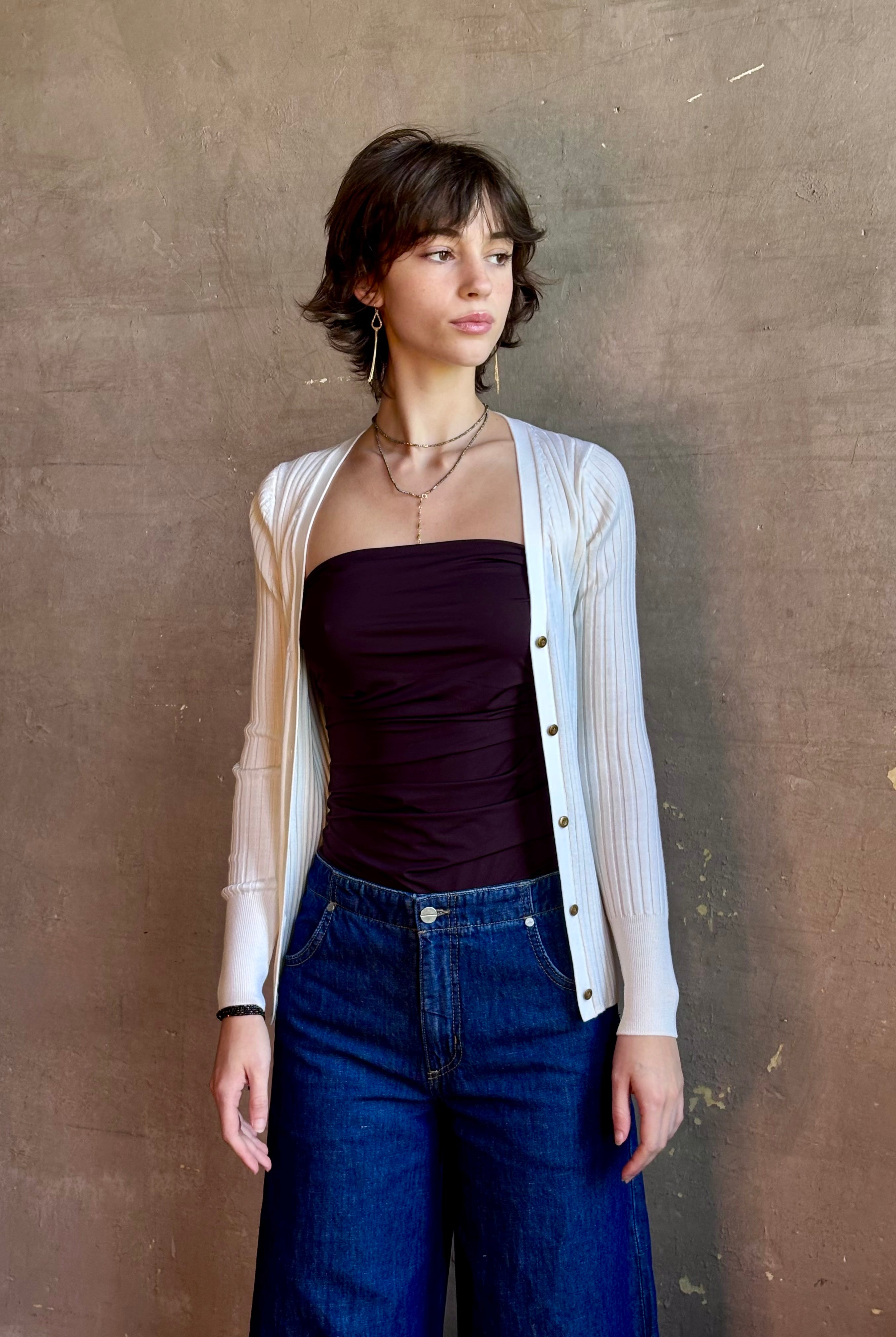 Woman wearing timeless luxury Italian knitwear by FORTE FORTE Superfine Merino Ribbed Cardigan in Neve off-white with v-neck, button front and long sleeves