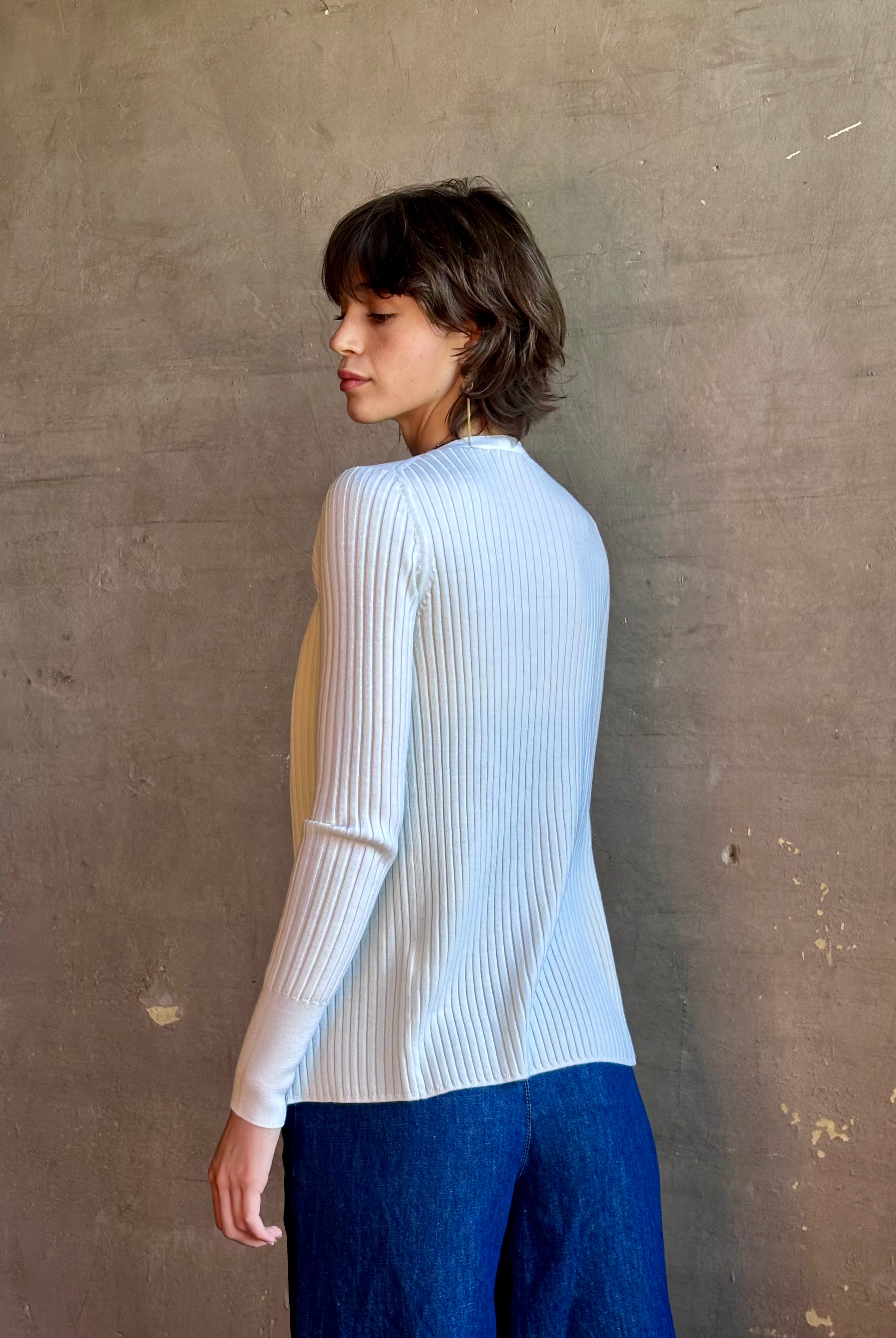 Woman wearing luxury Italian knitwear by FORTE FORTE Superfine Merino Ribbed Cardigan in Neve off-white with v-neck, button front and long sleeves