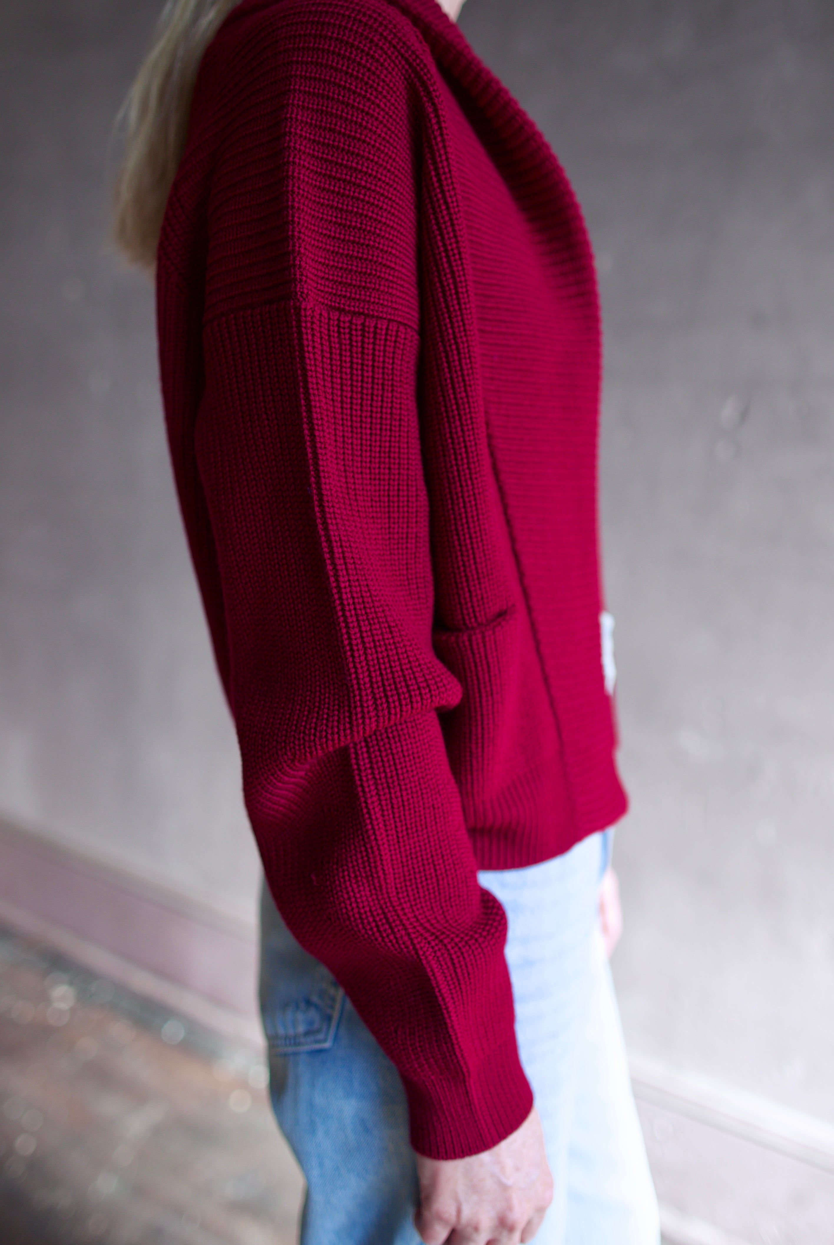 Model wearing a ruby red Forte Forte Merinos cardigan featuring a shawl wrap collar and long sleeves in vrigin wool