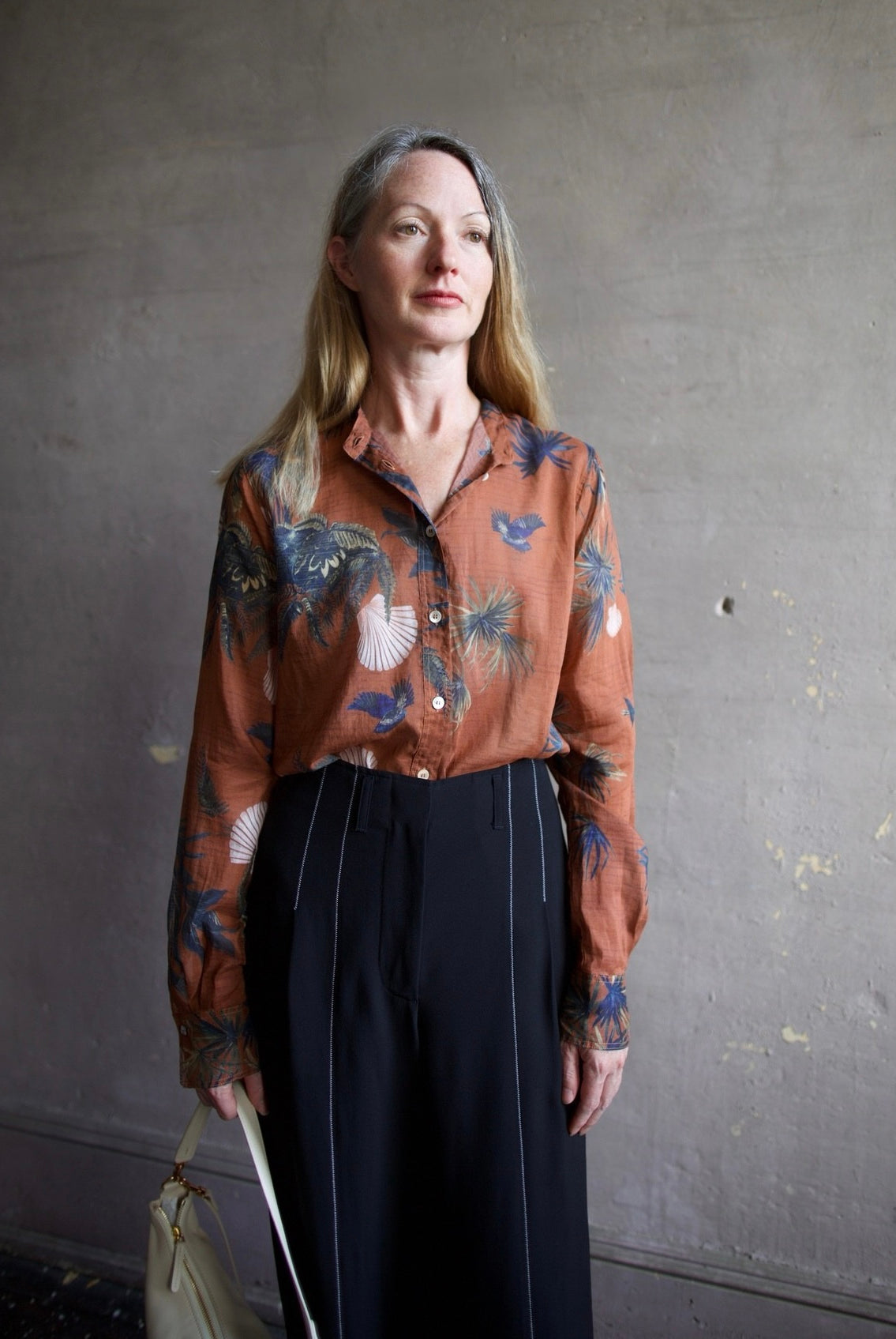 Woman wearing the Coreana voile shirt by Forte Forte in a lightweight cotton silk body and a teal fauna print with pink sea scallop shells.