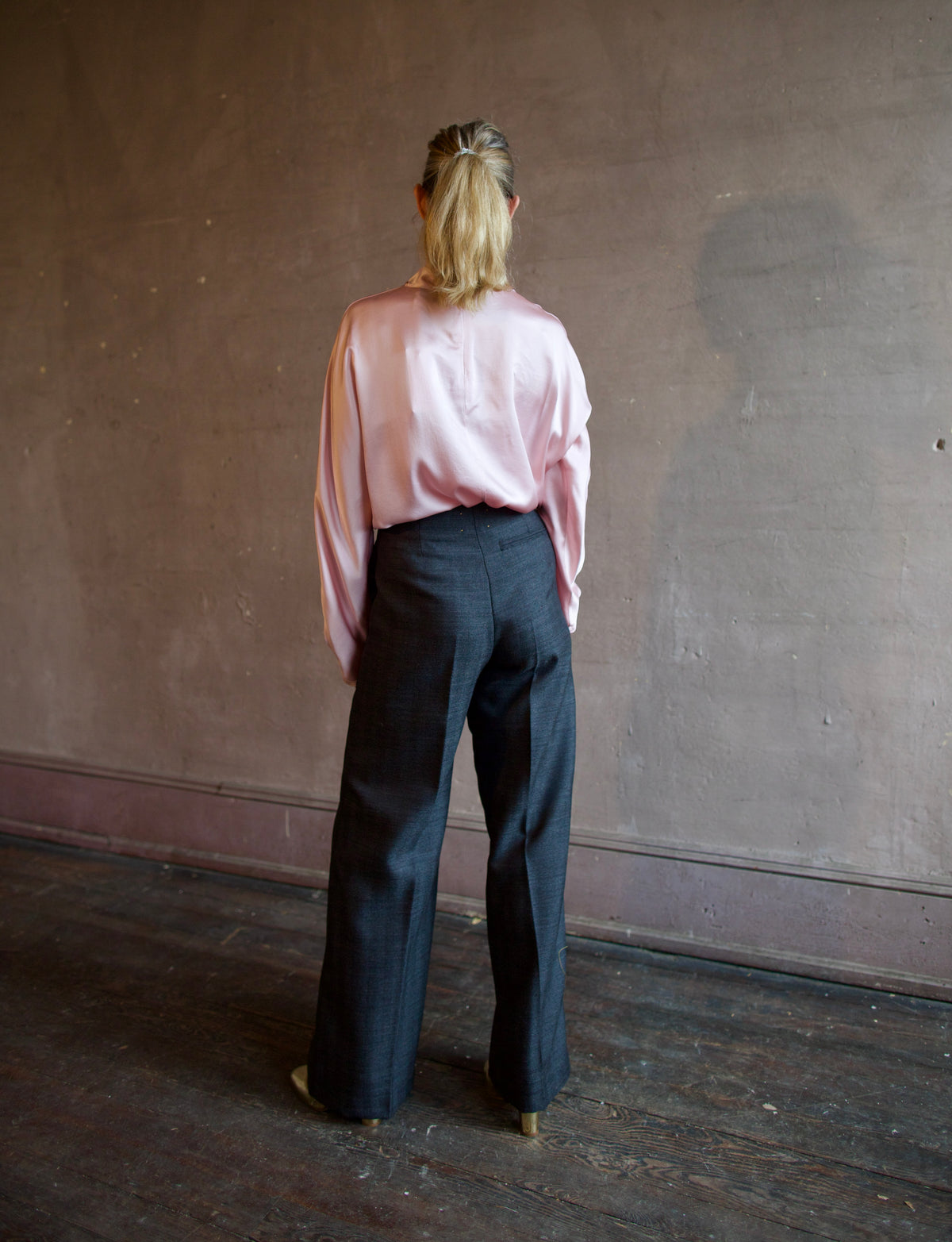 Mature woman wearing Forte_Forte's tailored Grey Herringbone Pants in virgin wool asymmetrical sequence embellishment down side