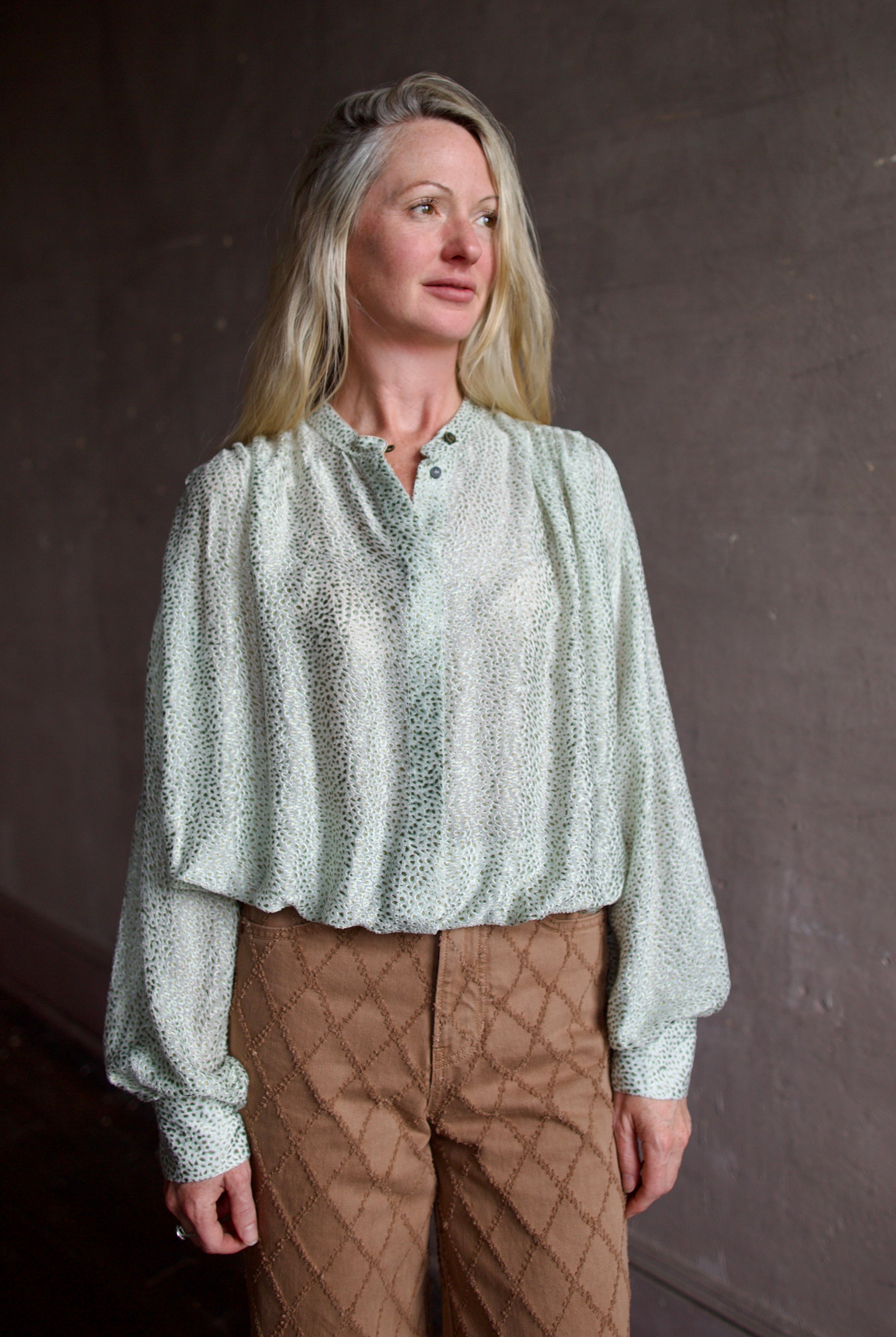 Mature model wearing a light weight white and mint green blouse from high-end fashion designer Forte Forte