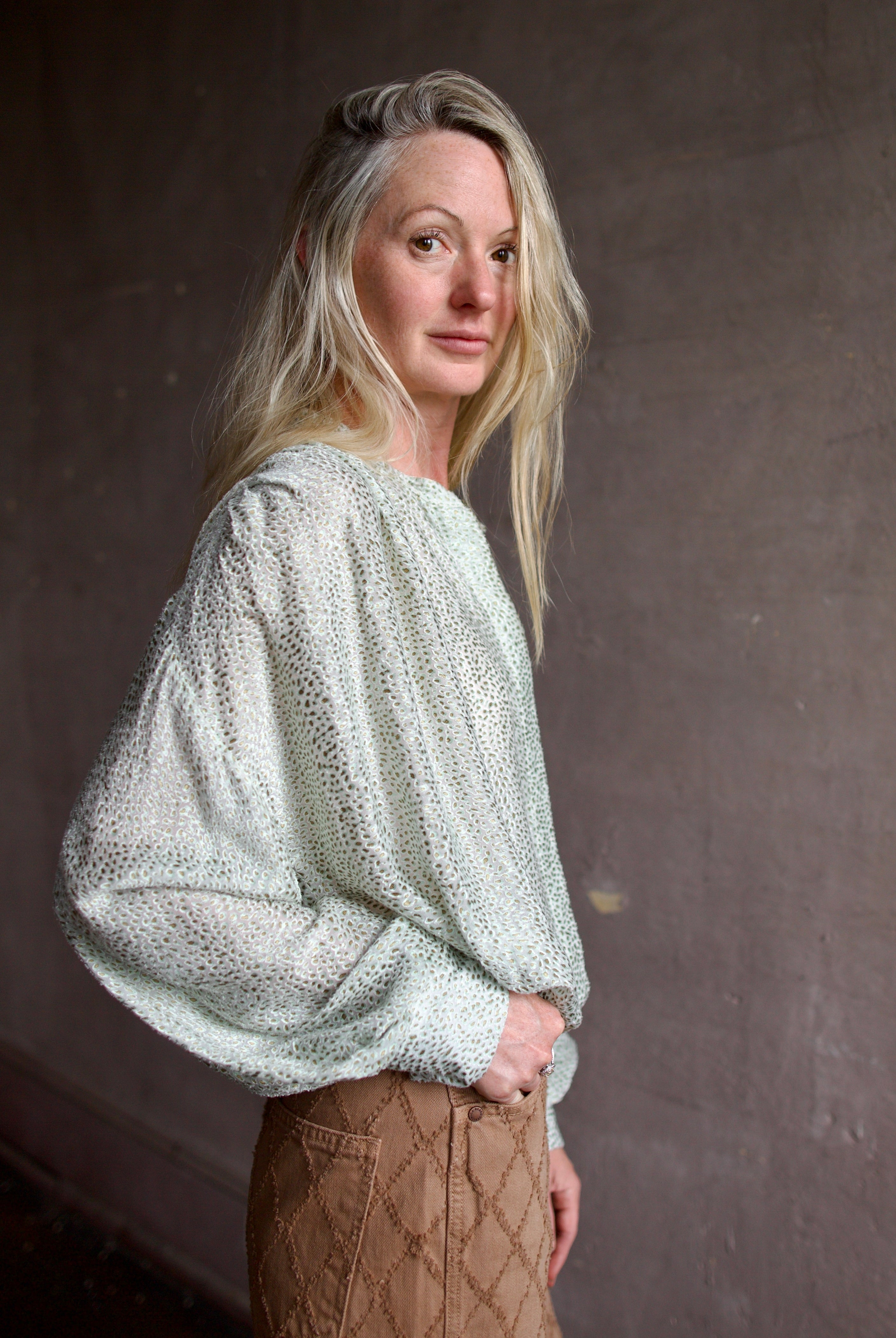 Mature woman wearing a light weight white and mint green blouse from high-end fashion designer Forte Forte