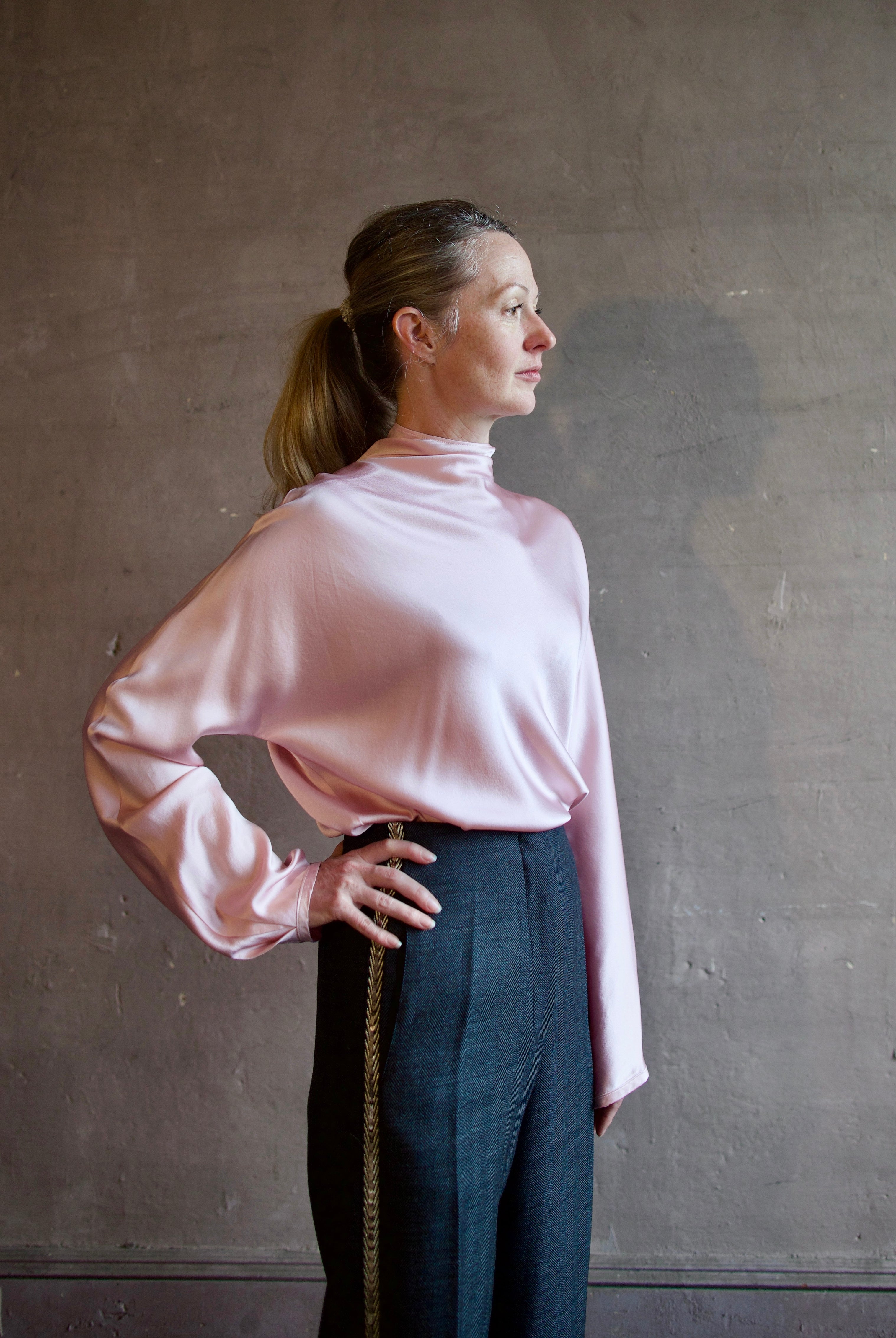 Image featuring a woman wearing the satin crater neck silk shirt by Forte Forte with s a high neckline, zip closure and a relaxed fit in a light pink color.