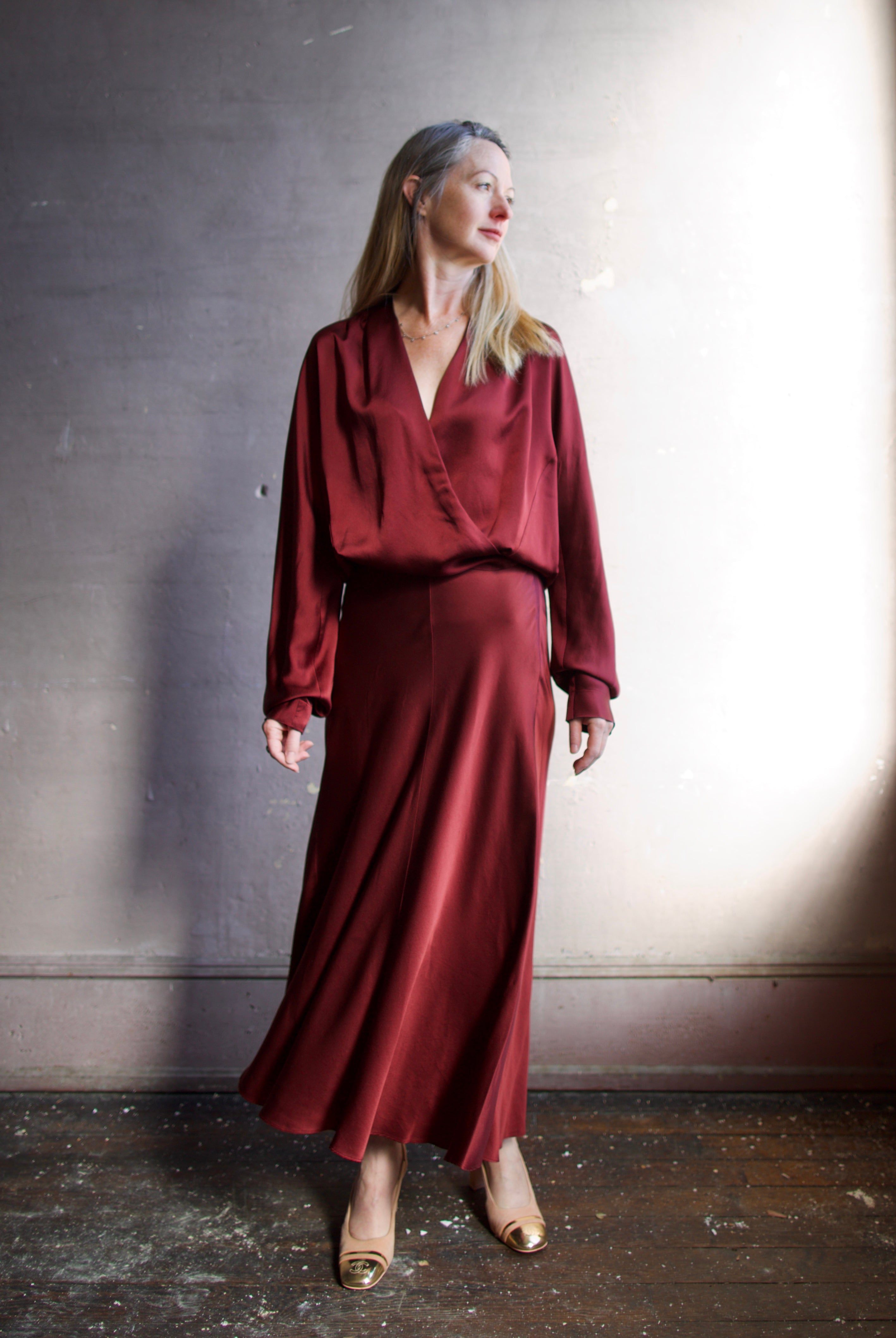 Image featuring a woman wearing the burgundy silk blouse by Forte Forte with wrap styling, long sleeves and an elastic waist.