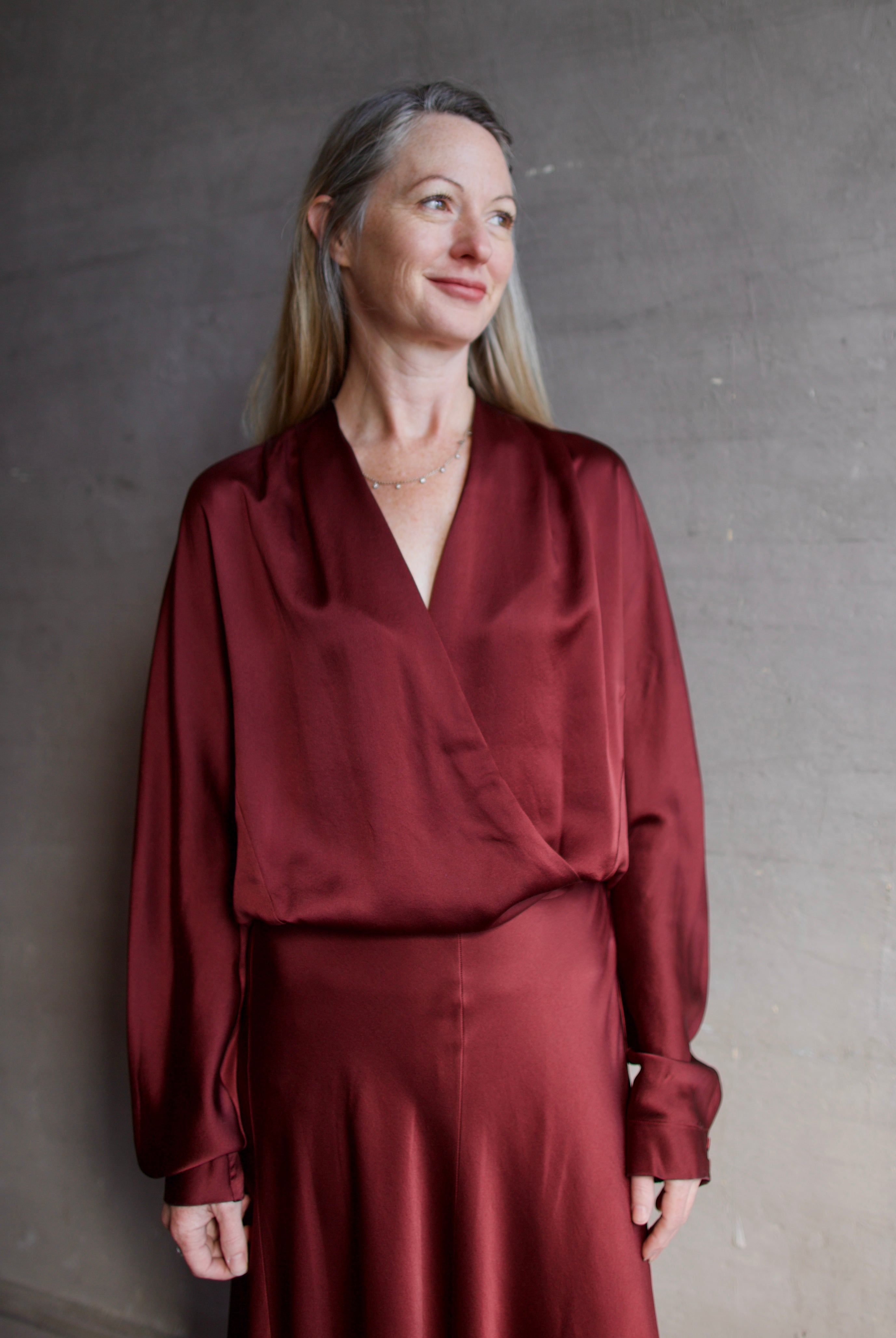 Image featuring a woman wearing the burgundy silk blouse by Forte Forte with wrap styling and an elastic waist.