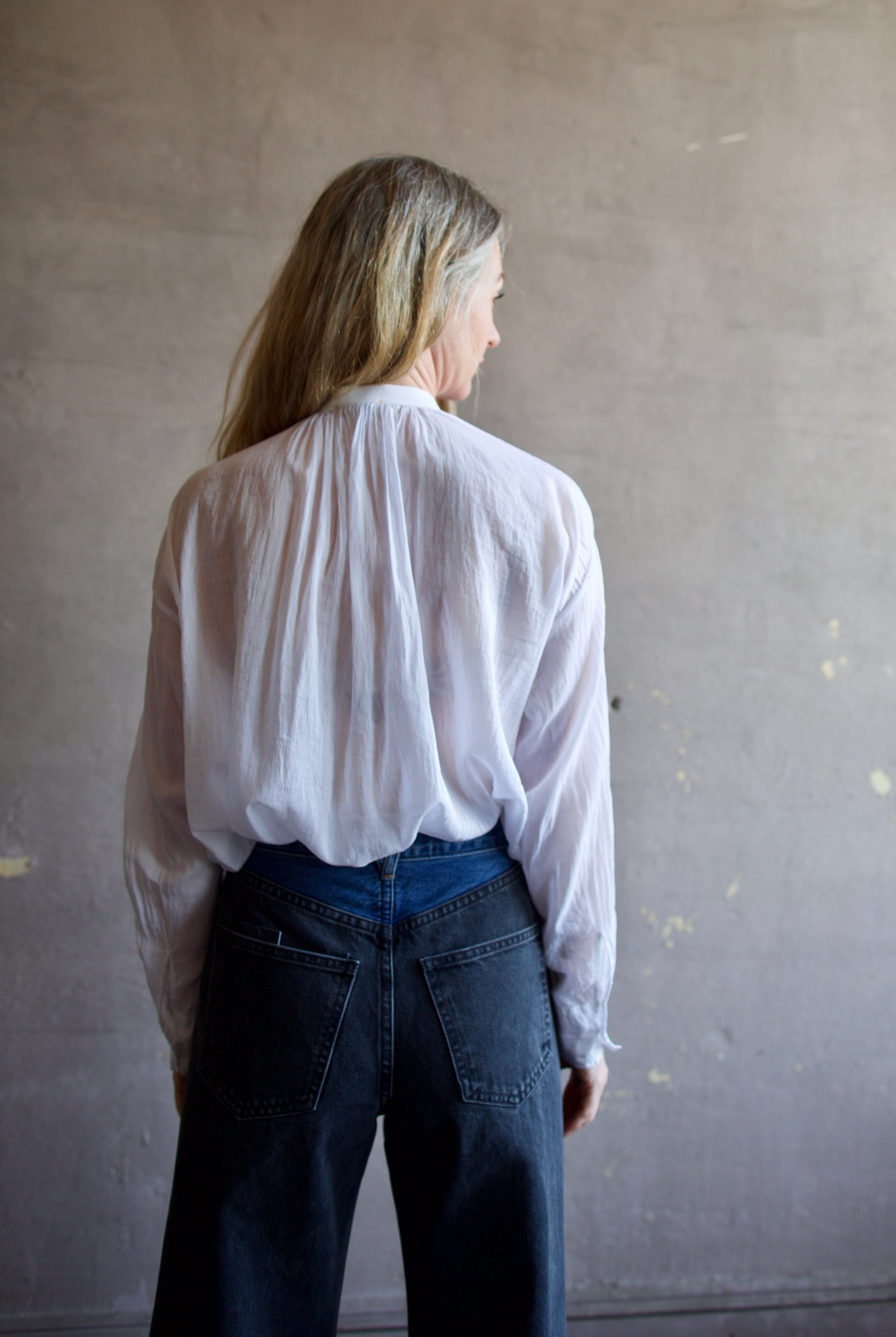 Image featuring a woman wearing the voile bohemian shirt by Forte Forte with a hook and eye closure and crystal embellishment at the mandarin collar and sleeve button.