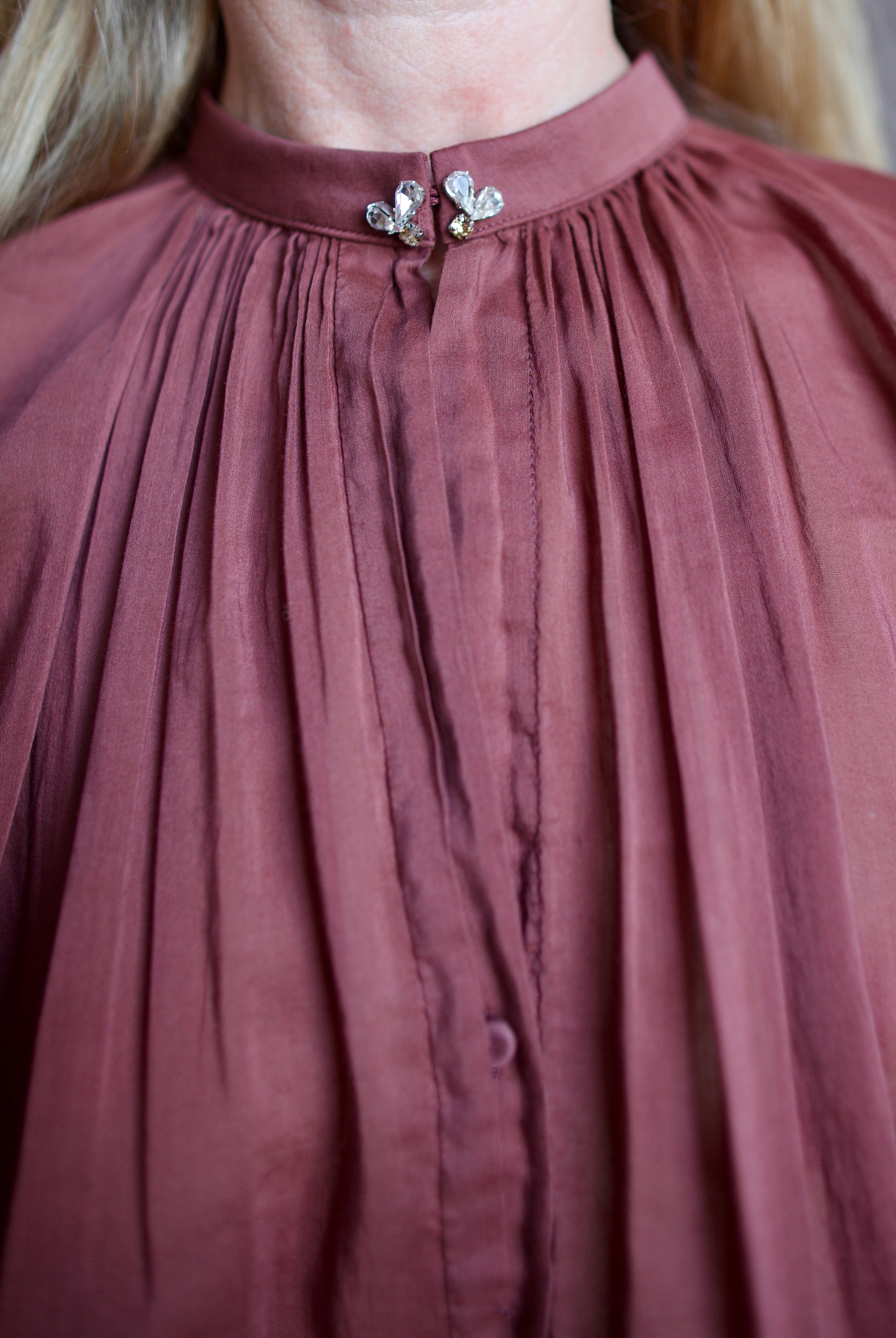 Image featuring a woman wearing the voile bohemian shirt by Forte Forte with a hook and eye closure and crystal embellishment at neckline and long sleeve button.