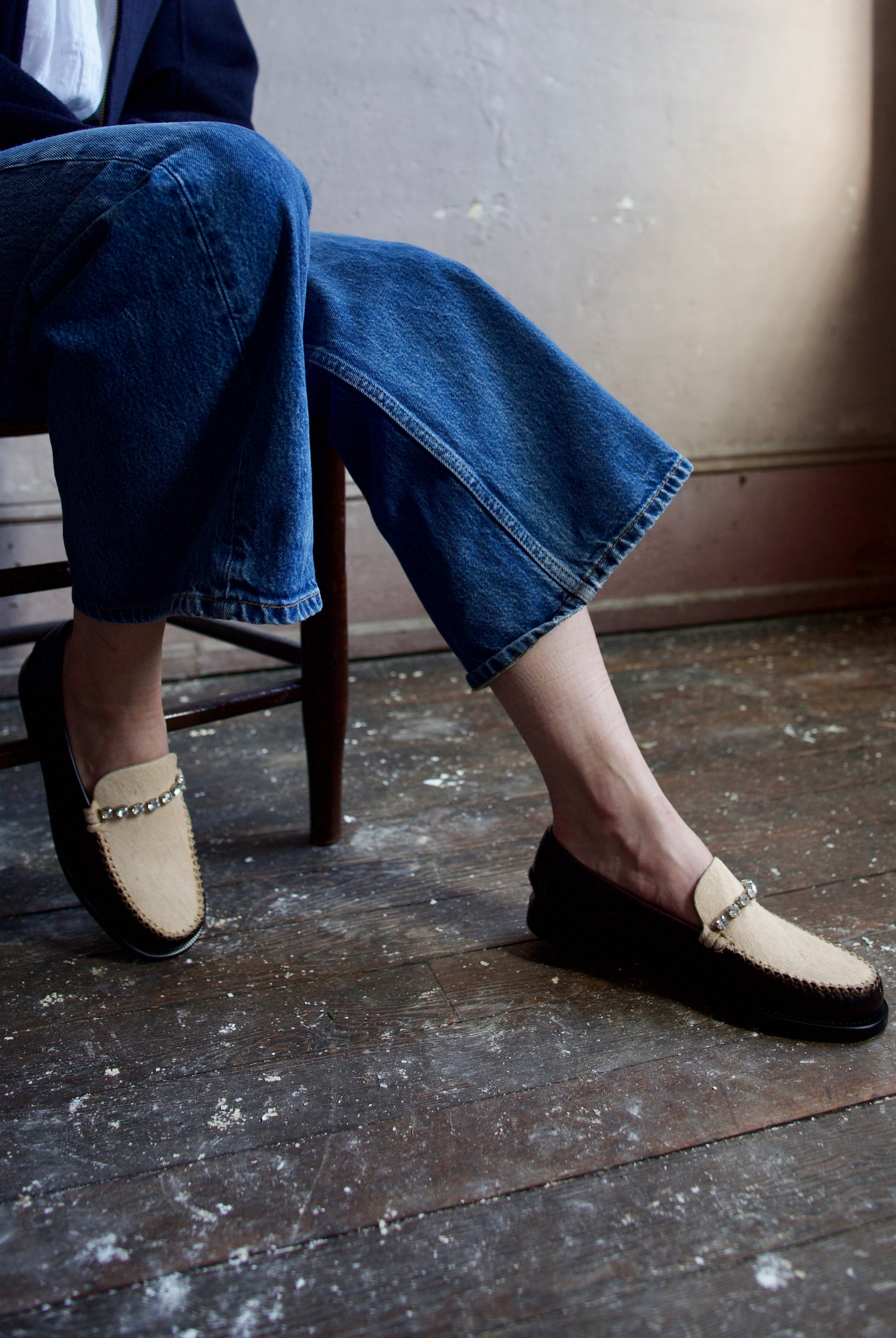 Image featuring a woman wearing the Forte Forte collaboration loafers with Sebago. They are brown leather with ivory horsehair accents and rhinestone detailing.
