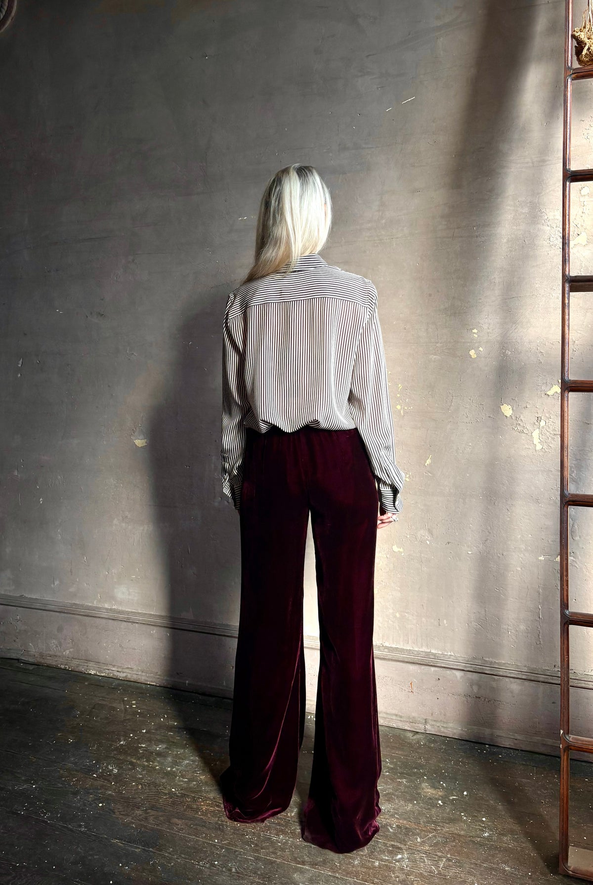 Back image of mature woman wearing Forte_Forte Plain Velvet Flare Pants in Burgundy with flexible elastic waistband at back