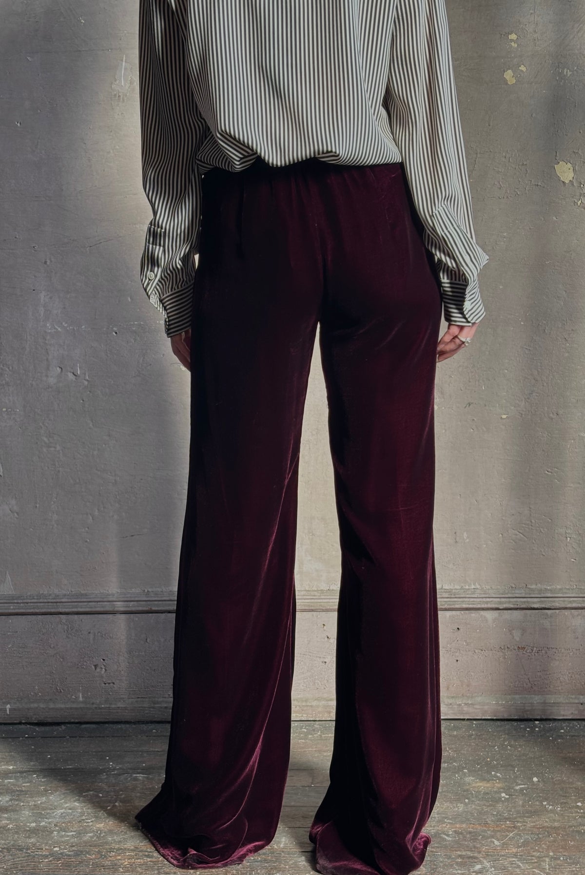Back image of mature woman wearing Forte_Forte Plain Velvet Flare Pants in Burgundy with flexible elastic waistband at back