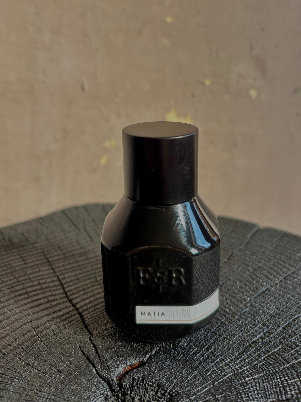 A small black bottle with a matching black cap with embossed F&R logo and a white label reading MATIA from Fulton and Roark made in USA