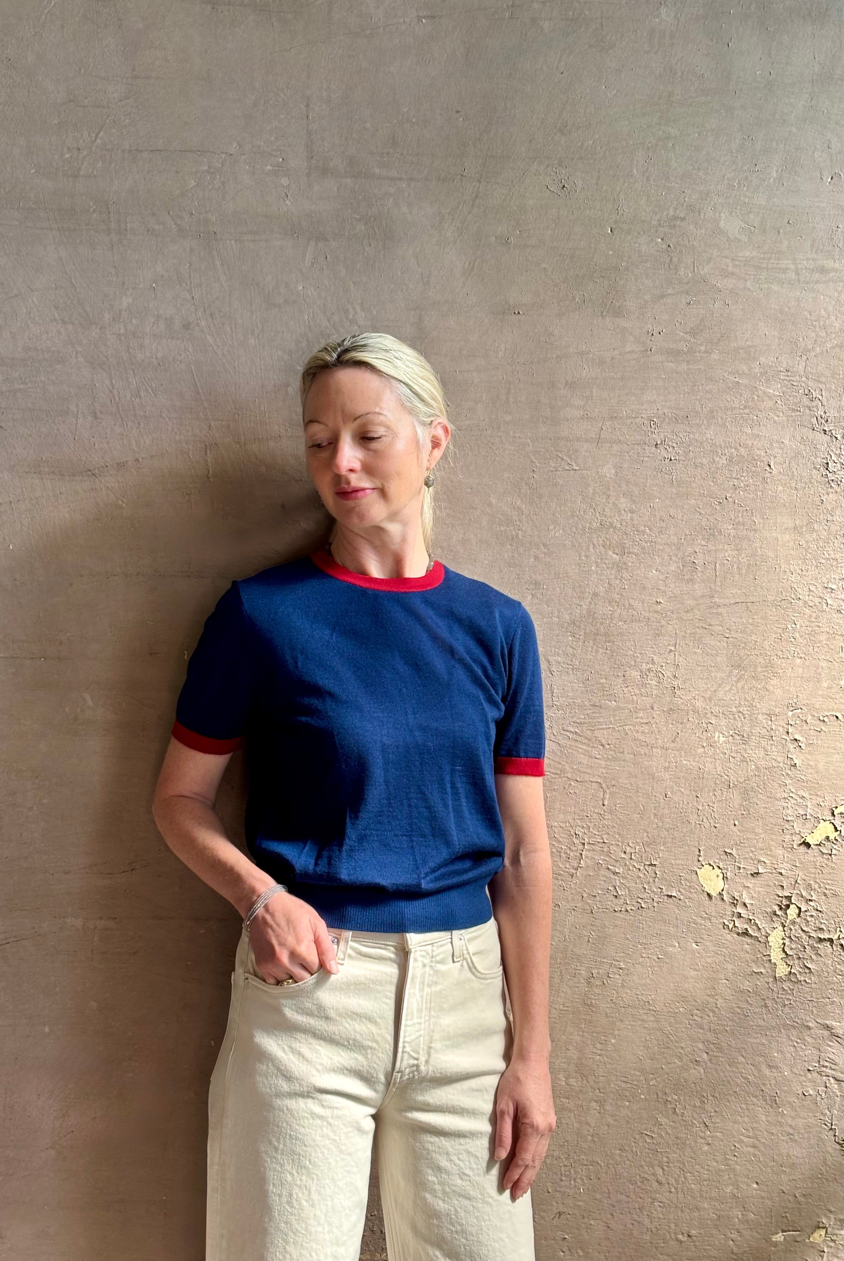 Mature woman wearing women's designer cashmere Airy short sleeve Ringer Tee from Guest in Residence rendered in a navy body with carmine ringer detailing and crafted from 100% lightweight cashmere with a crew neckline