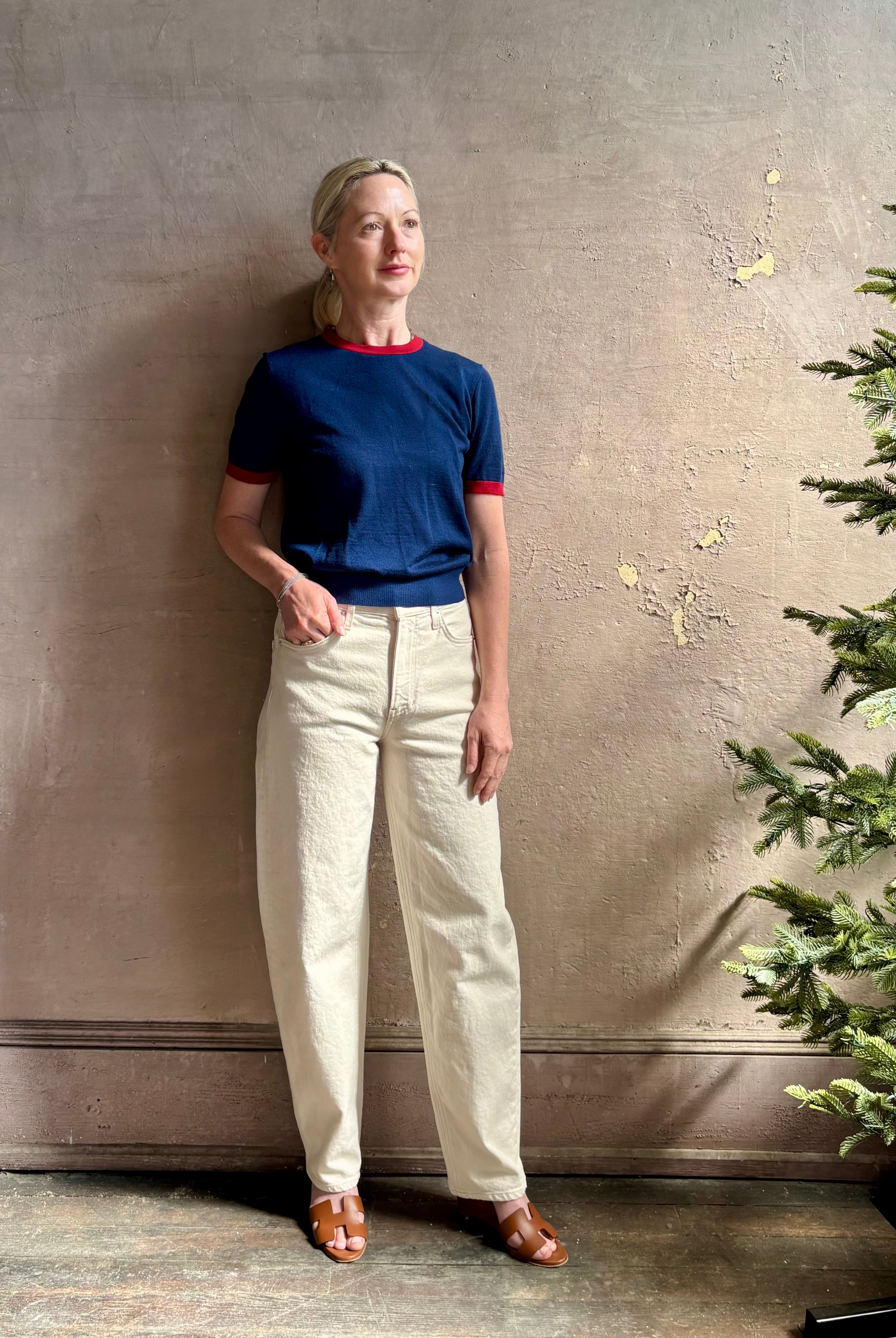 Mature woman wearing women's designer cashmere Airy short sleeve Ringer Tee from Guest in Residence rendered in a navy body with carmine ringer detailing and crafted from 100% lightweight cashmere with a crew neckline